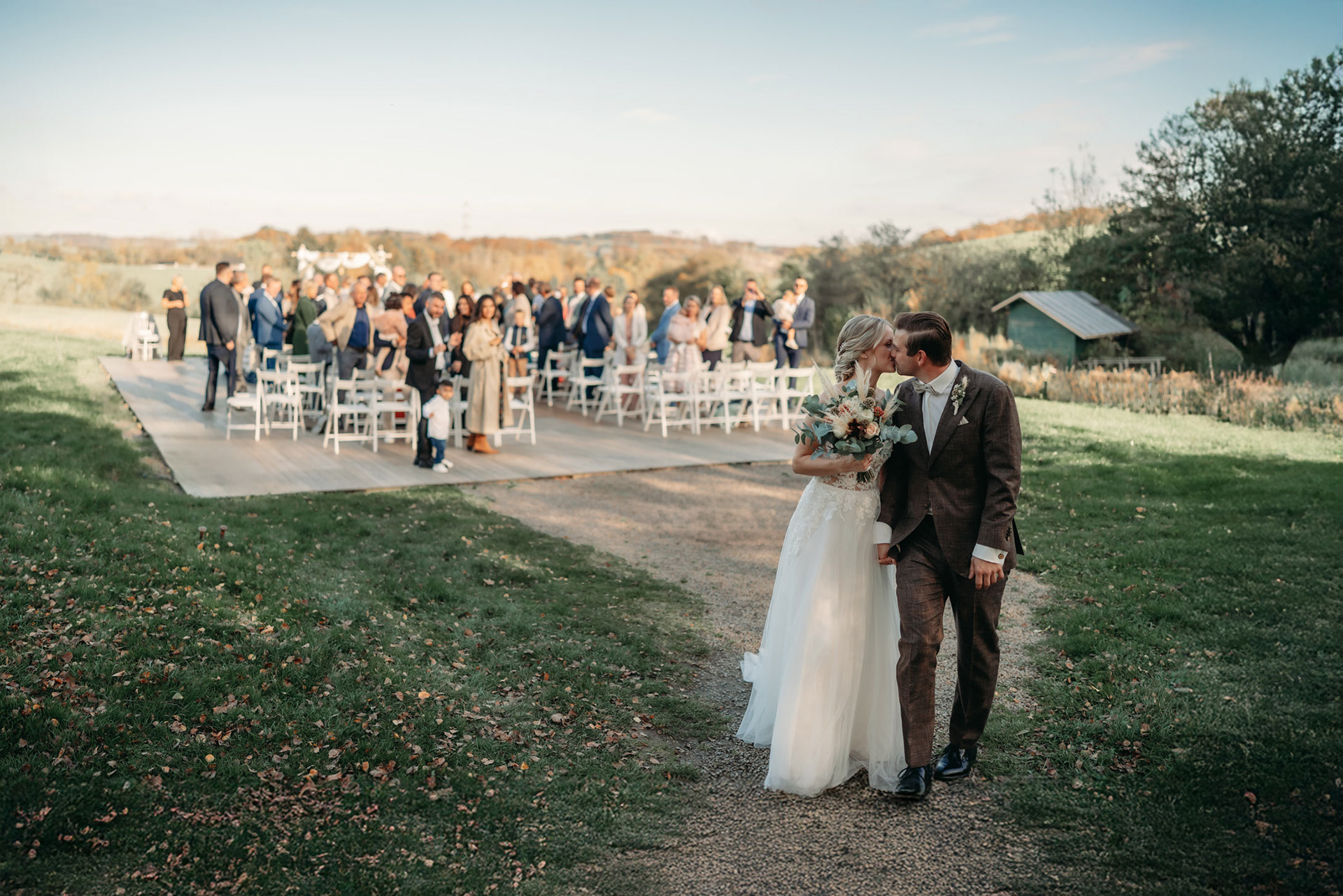 Hochzeitfoto Paar küsst sich vor Hochzeitsgesellschaft