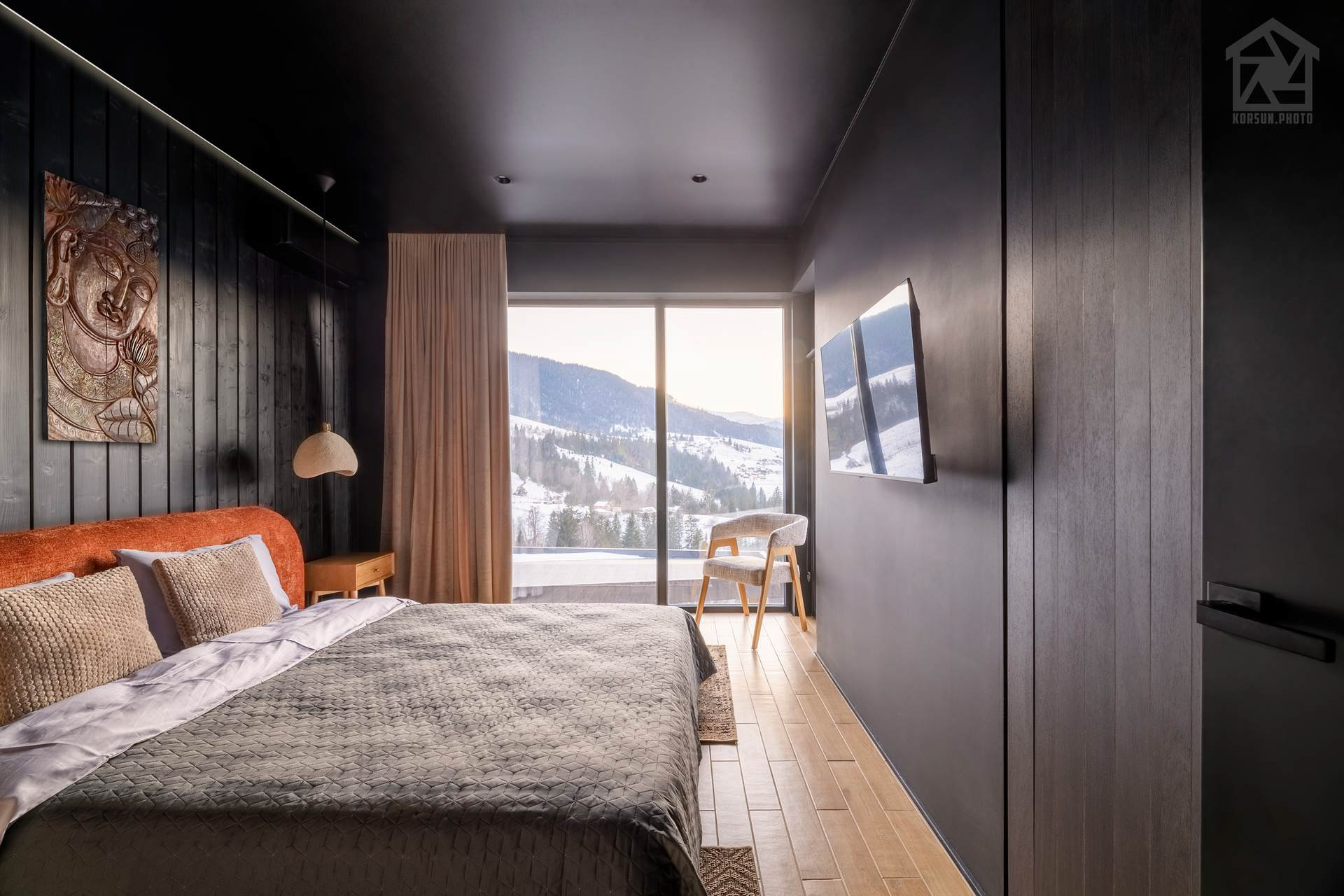 Спальня котеджу з панорамним вікном від підлоги до стелі та видом на гірські вершини