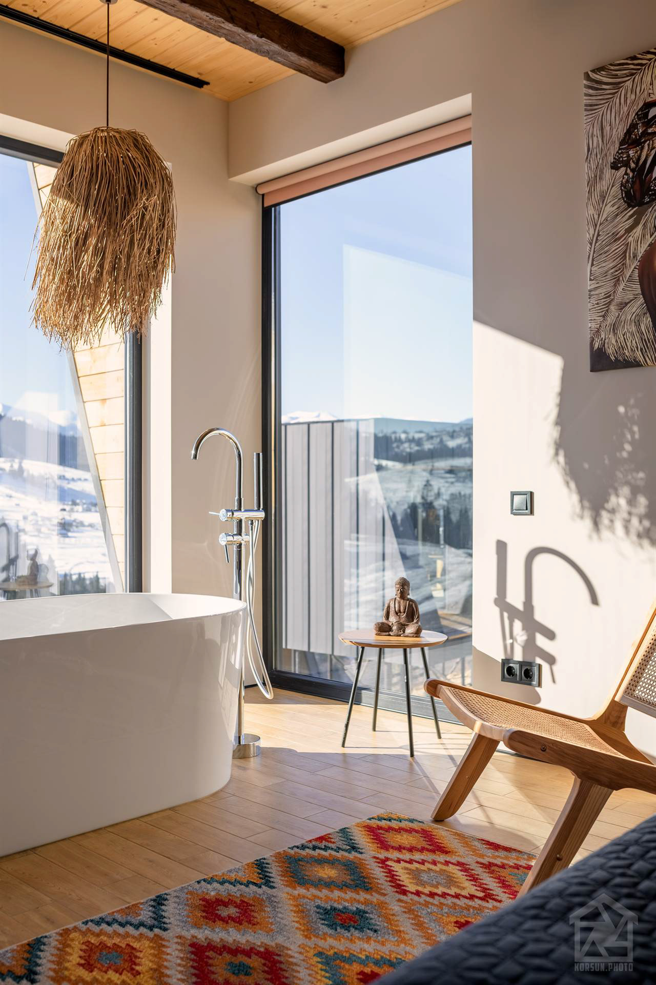 Загальний вигляд спальні з ліжком і ванною у просторі, наповненому природним світлом з панорамного вікна