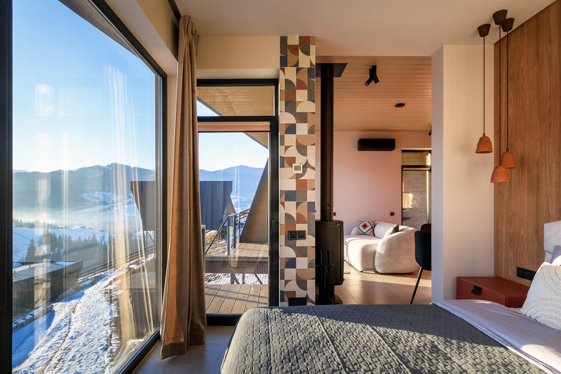 Спальня котеджу з великим панорамним вікном і видом на гірські схили