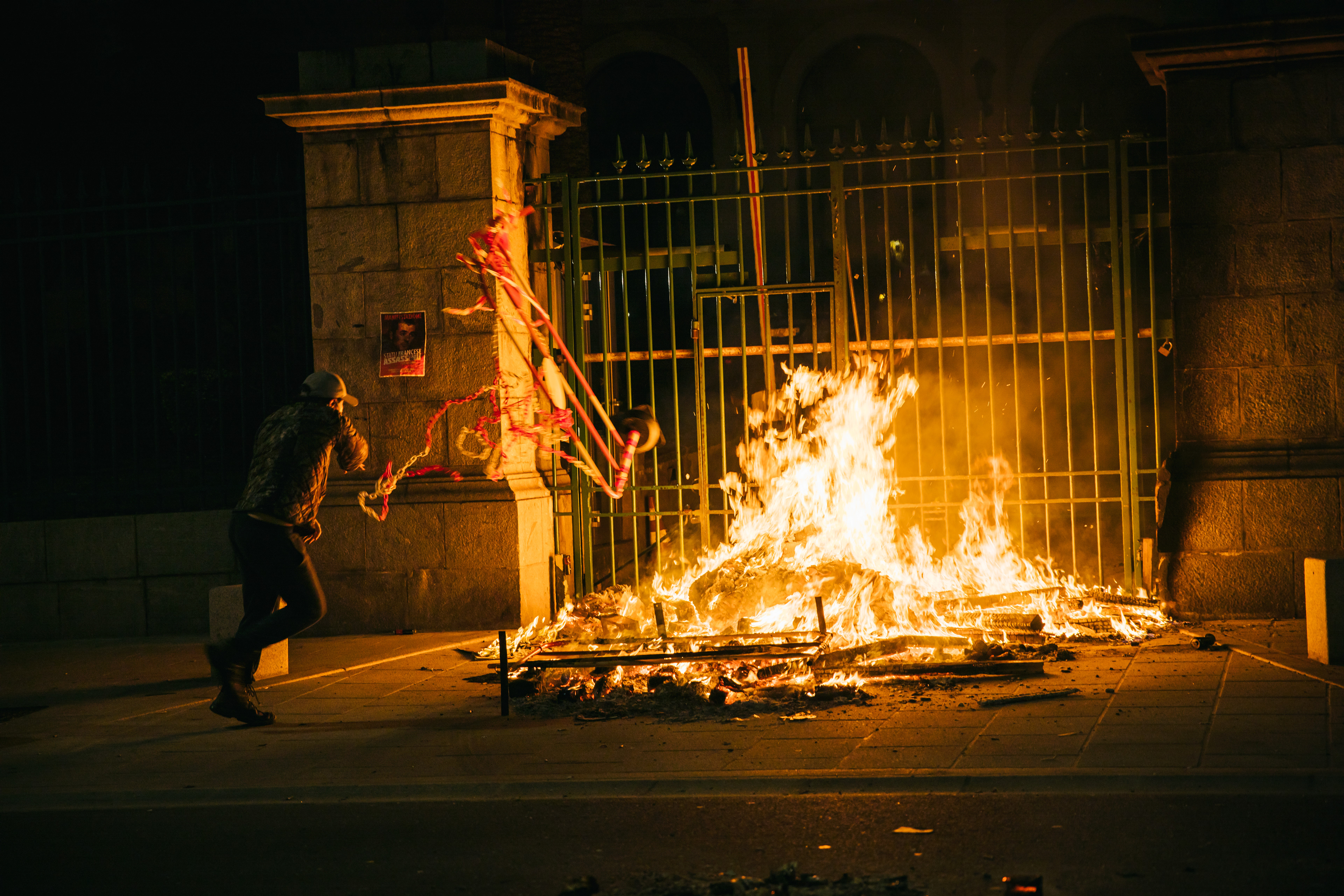 Un homme jette une barrière dans un feu allumé devant les grilles de la préfecture de Corse-du-Sud lors d'un rassremblement en soutient à Yvan Colonna - Ajaccio, 04/03/2022