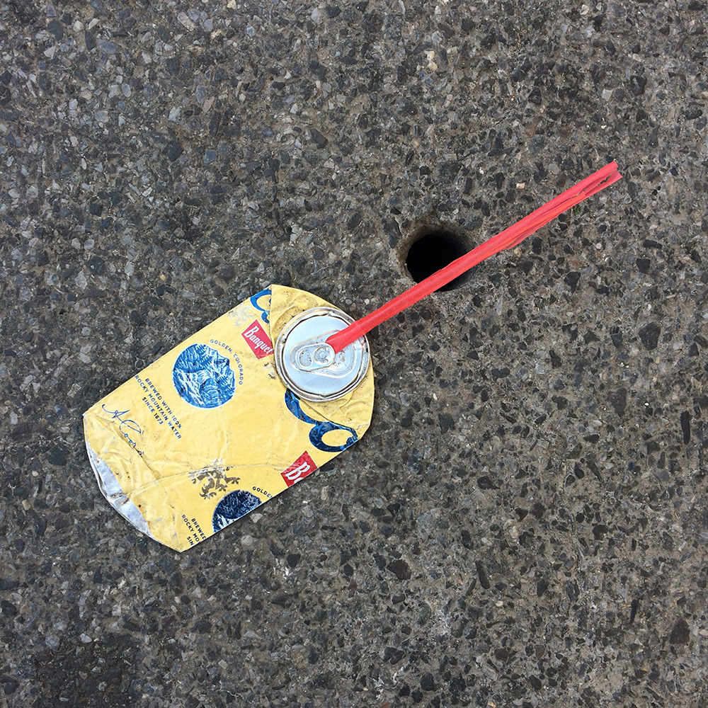 A photo of lost or discarded material found on a city street—with a form interpreted as resembling an oilcan.