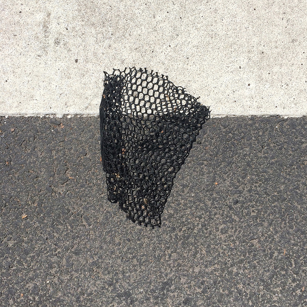 A photo of lost or discarded material found on a city street—with a form interpreted as resembling a basketball hoop