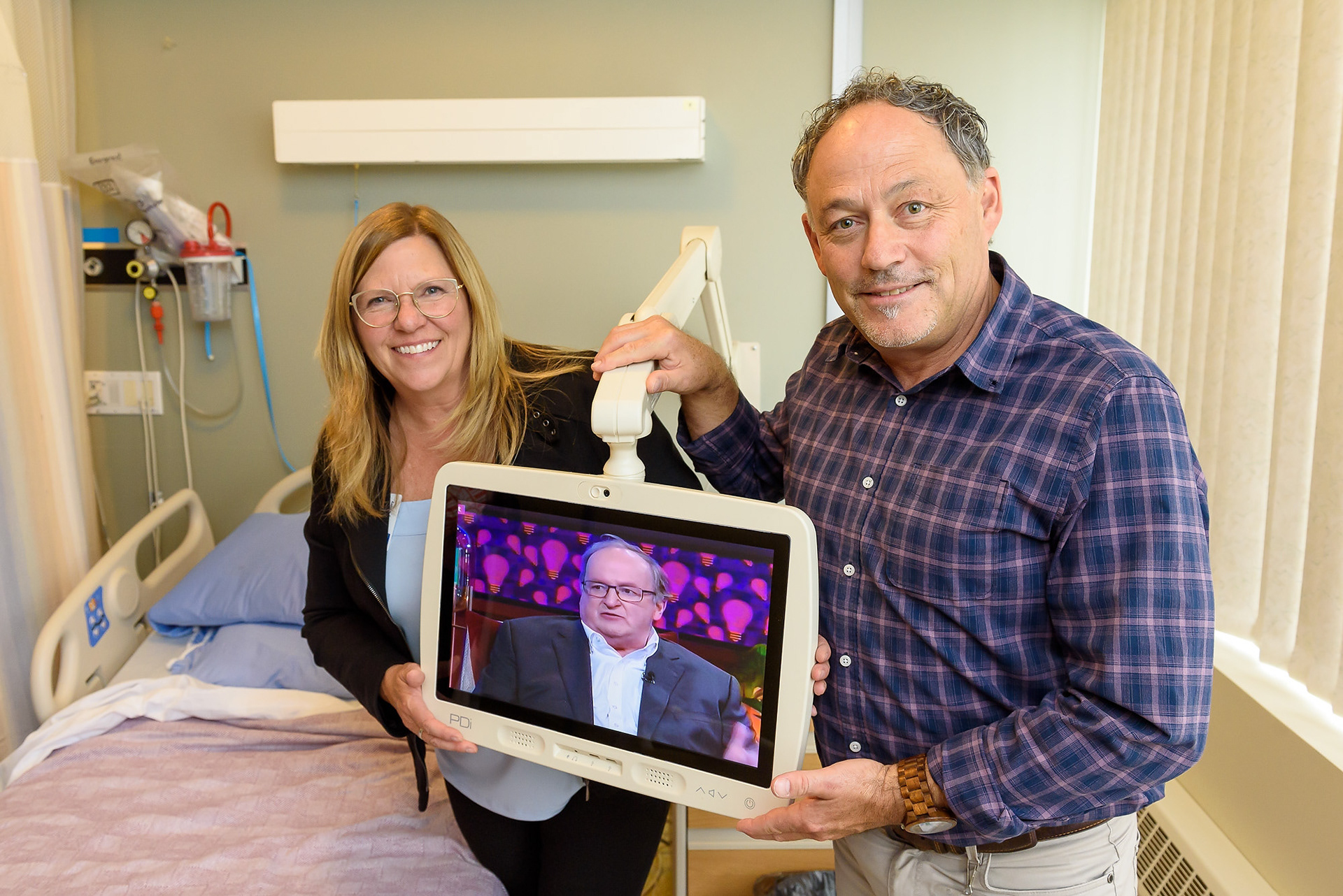 Cathy Couey, fund development officer of the High River District Health Care Foundation, left, and Darrin Parkin, chaplain at the High River Hospital, display a new Patient Entertainment System at the hospital's acute care ward in High River on Sept. 27, 2023.