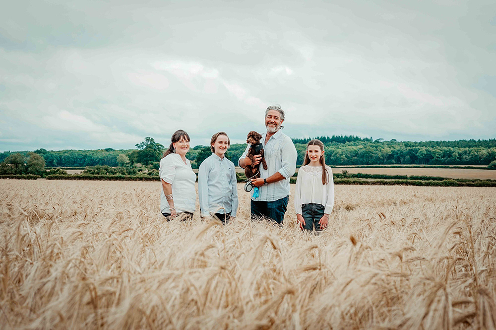 happy family stood in wheat field in oxfordshire england near blenheim palace with portrait photographer david lefebvre