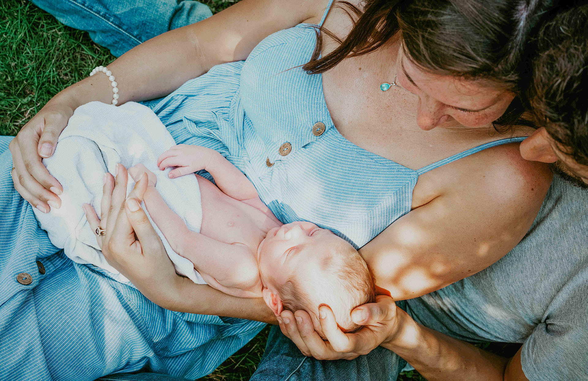 photo by david lefebvre of young parents sat on grass under tree with newborn photographer