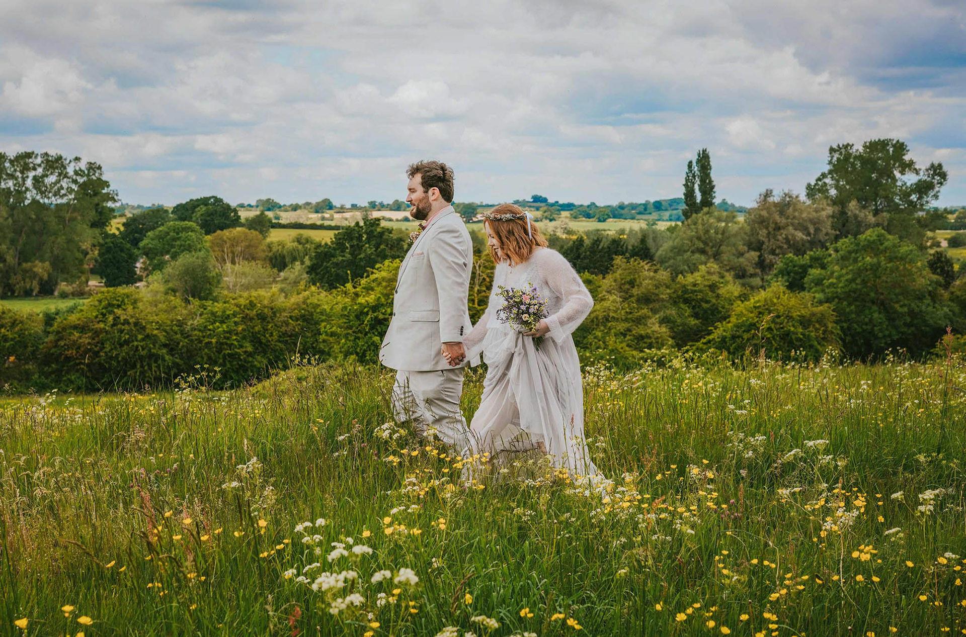 dramatic image of bride and groom smiling walking together in somerton meadow near bicester by david lefebvre a wedding photographer from buckinghamshire