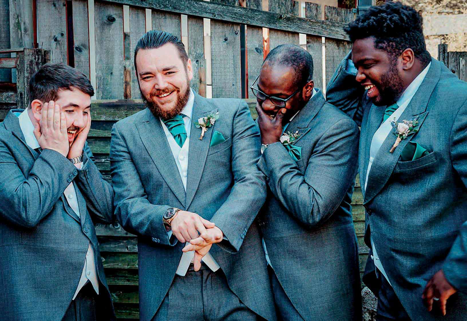 funny groom and groomsmen photo of groom pretending to show off brides ring in garden getting ready and laughing together in manchester taken by wedding photographer david lefebvre