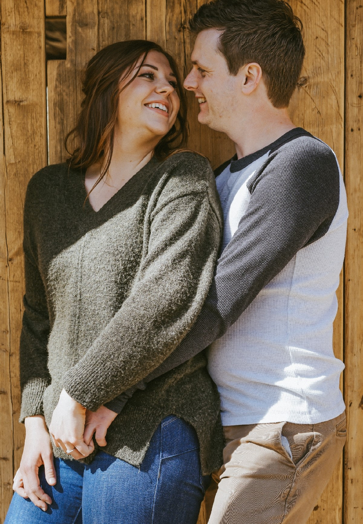 couple stand arm in arm smiling on engagement pre wedding photoshoot in woodland wedding venue in swanbourne