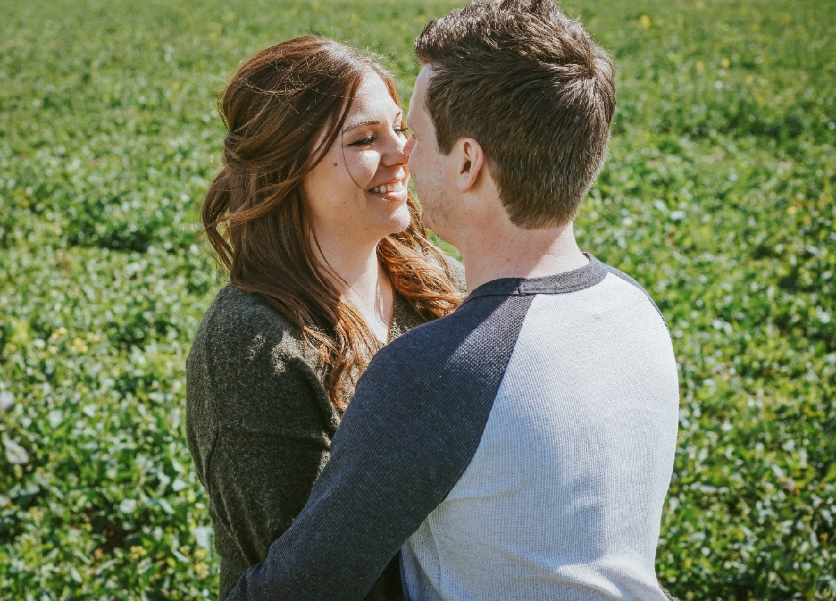 wedding photographer david lefebvre photo of couple close up of couple smiling holding each other in rapeseed field in swanbourne uk on pre wedding engagement photo shoot session