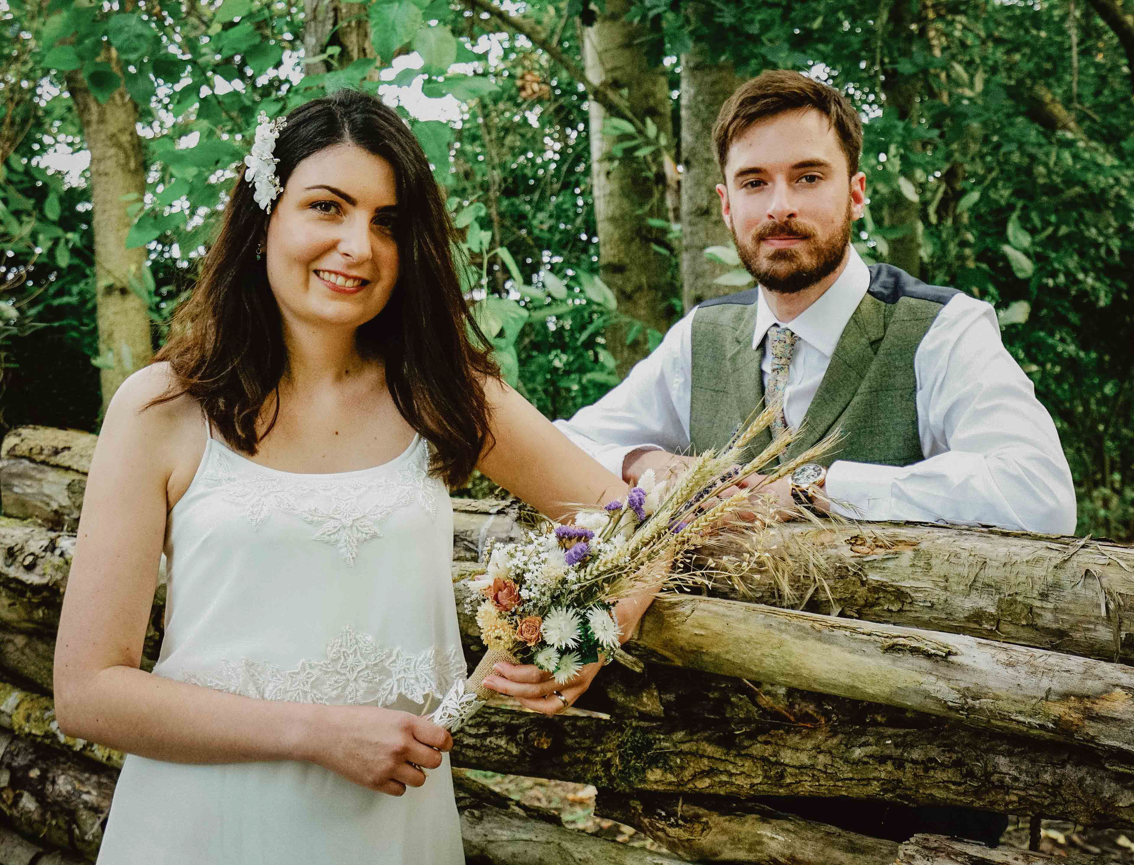 candid photo of adventurous bride and groom stood by log pile in green endeavour woodland wedding venue with david lefebvre buckinghamshire swanbourne photographer