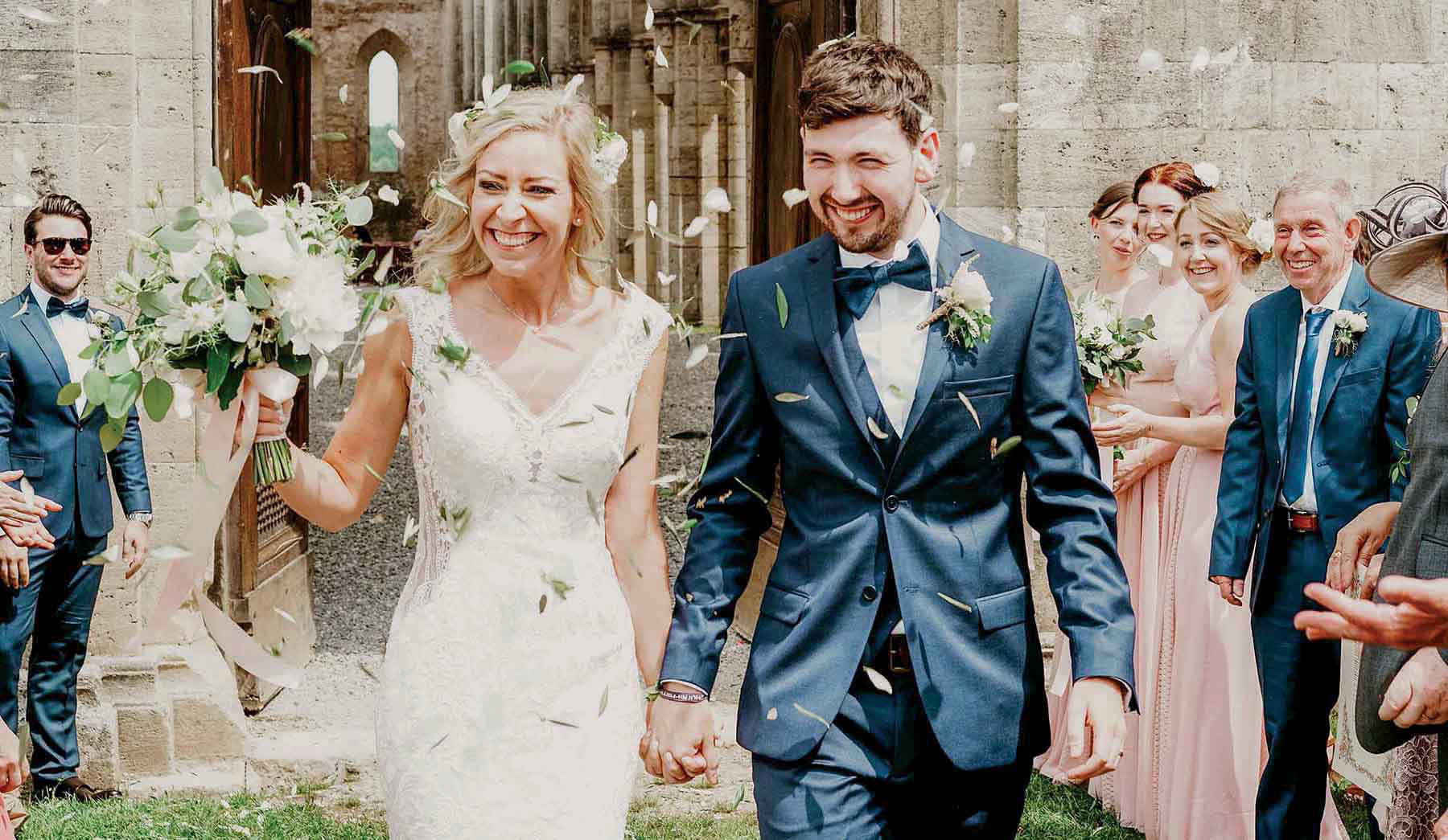 bride and groom leaving san galgano abbey in italy married in the summer down confetti aisle with destination wedding photographer-david lefebvre from buckinghamshire uk