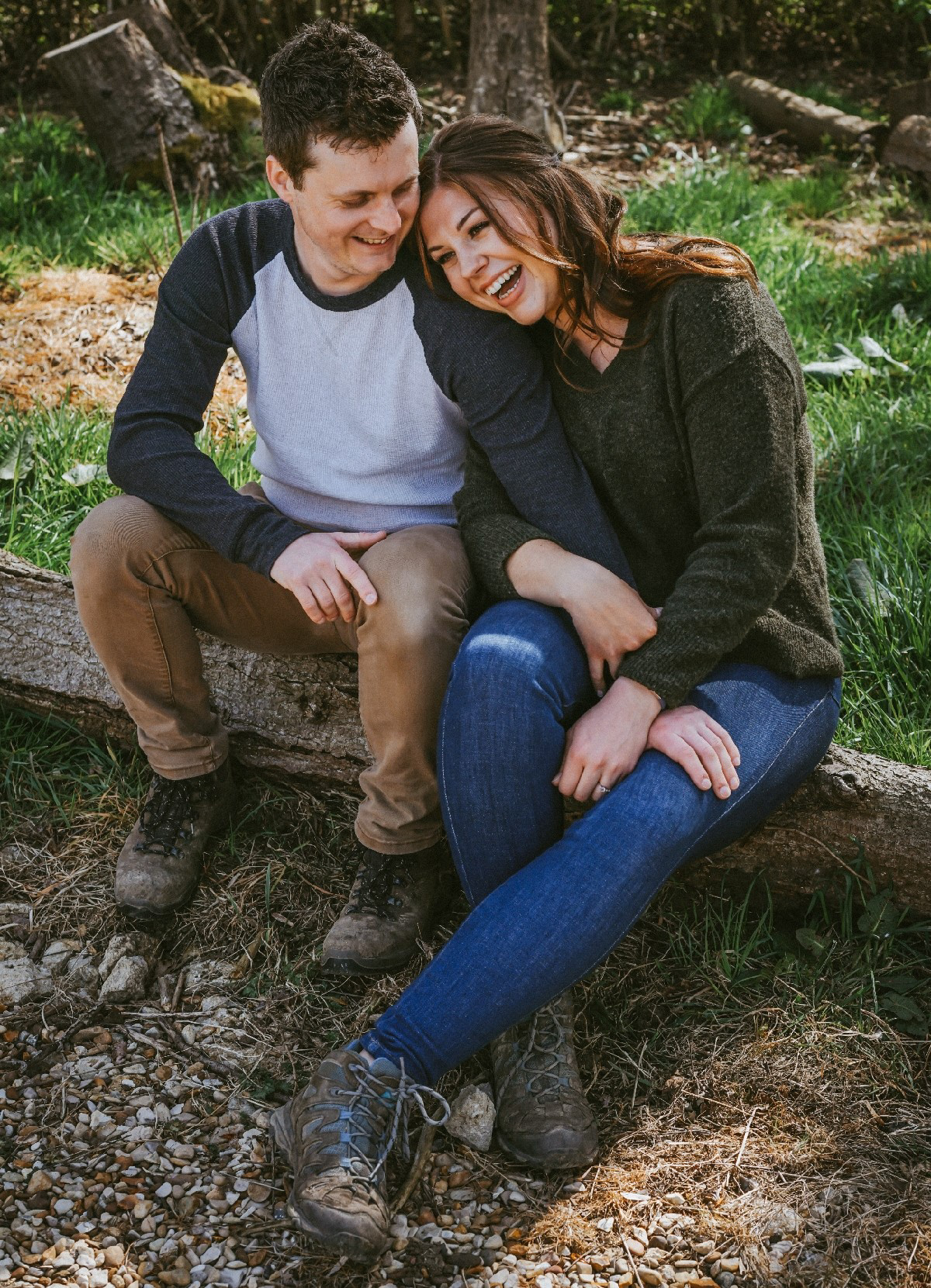 candid photo of happily engaged couple with soon to be bride laughing hysterically at fun woodland at pre wedding photo shoot session with david lefebvre a wedding portrait and product photographer from buckinghamshire uk the photo has been edited with warm colours