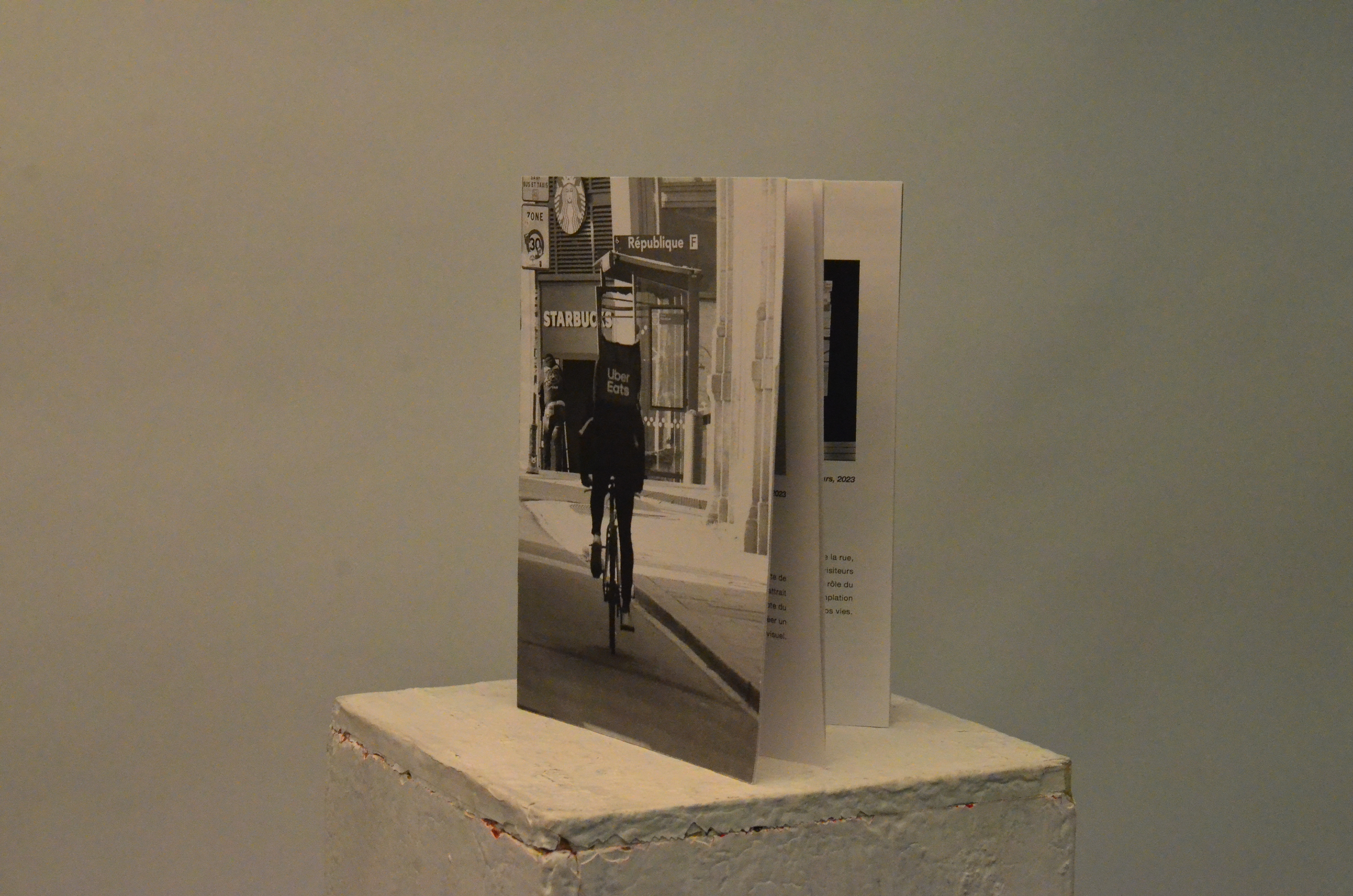 Exposition Hubert, Galerie Awen, Rennes, L'exposition explore les questions soulevées par la livraison de repas à domicile effectuée par des travailleurs indépendants et examine plus largement l'impact de l'ubérisation sur notre société.  Le concept de l'exposition découle d'une observation fondamentale : les consommateurs sont pris entre deux influences contradictoires. D'un côté, l'éthique les pousse à rejeter cette forme d'esclavage moderne, tandis que de l'autre, la commodité et la rapidité offertes par ce service semblent irrésistibles. Cette tension s'inscrit dans un contexte plus vaste au sein de notre société, à savoir l'ubérisation. Cela se traduit par une réduction du rôle humain au profit d'algorithmes omniprésents, agissant comme des intermédiaires entre les clients et fournisseurs (en l’occurence clients de restauration rapide et livreurs à vélo), à portée de clic. L'exposition vise à offrir un regard sur cette profession souvent invisible, celle des livreurs. « Pour explorer ces thèmes, j'ai eu recours à des méthodes anthropologiques, à des installations artistiques, ainsi qu'à l'utilisation d'une intelligence artificielle qui génère des visages. Ces éléments combinés mettent en lumière la place de l'humain au sein de cette profession en constante évolution. » © Elsa Tessier 