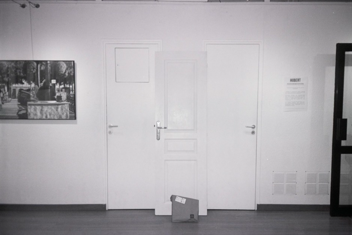 Exposition Hubert, Galerie Awen, Au pied de la porte, installation, 4mx2m, 2023. Deux portes closes faisant partie de la galerie, devant lesquelles est placée une troisième porte avec à ses pieds un sachet de nourriture livré. Cette installation, composée de trois portes, présente la réalité du quotidien des livreurs pendant la pandémie de COVID-19, qui ont été contraints de déposer des repas devant des portes fermées. Le visiteur est à la place du livreur, confronté à cette réalité déshumanisante.. © Elsa Tessier