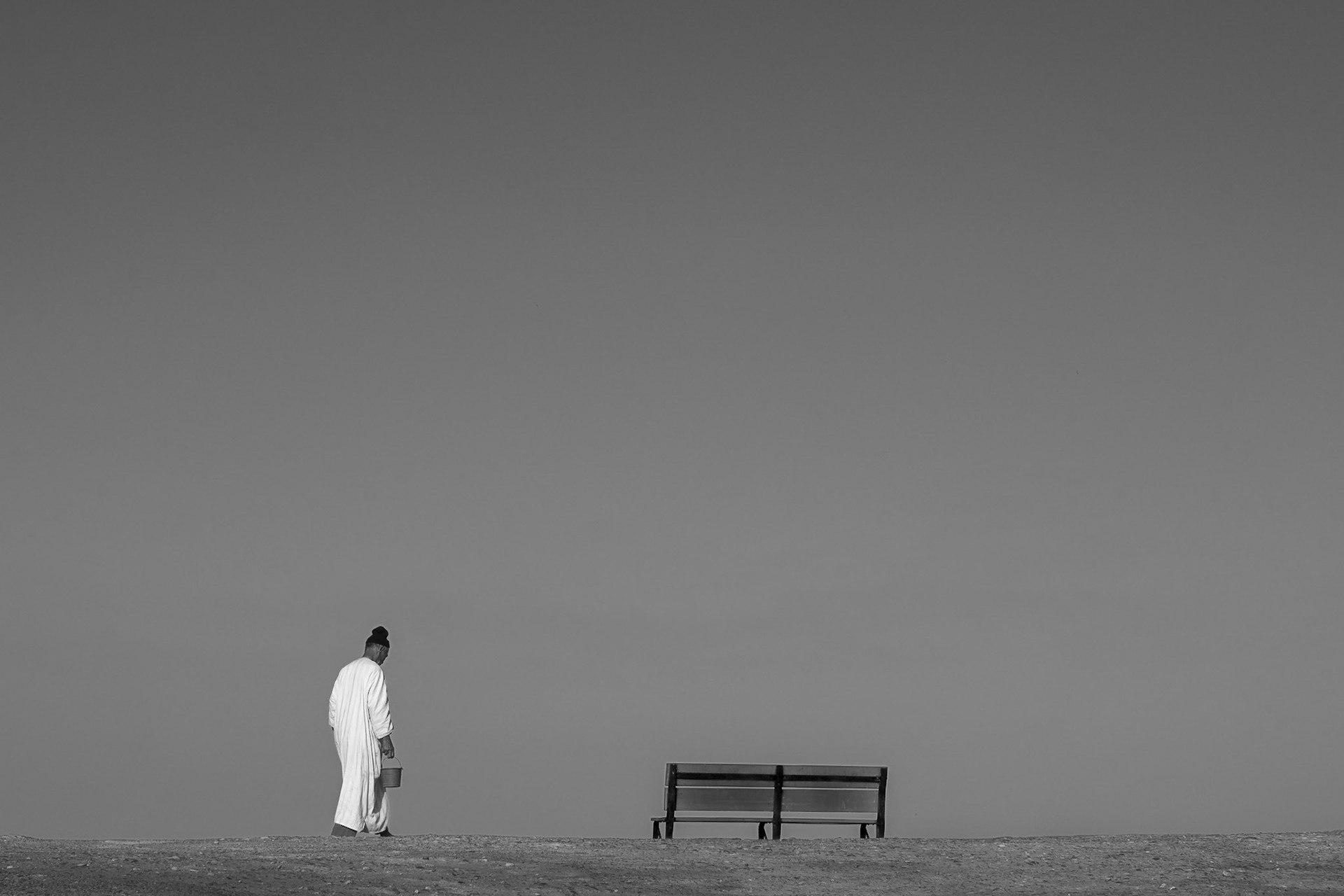 Man walk alone cross a bench