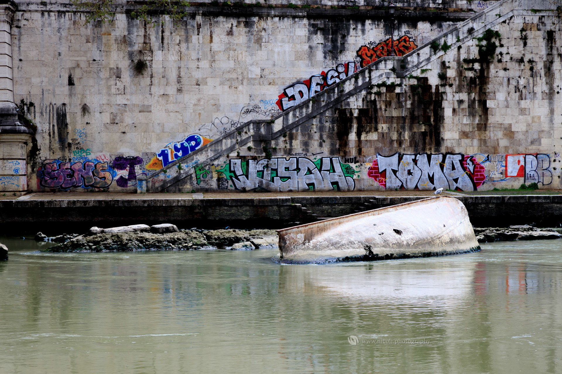 ROME, ITALY - APR 12, 2019: Tiber river contaminated with trash and graffiti.