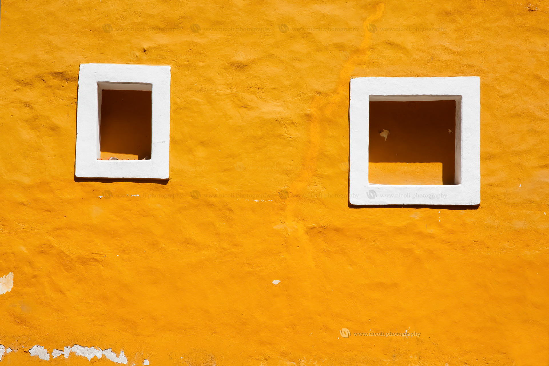 Old yellow wall and window in Coyoacan, Mexico.