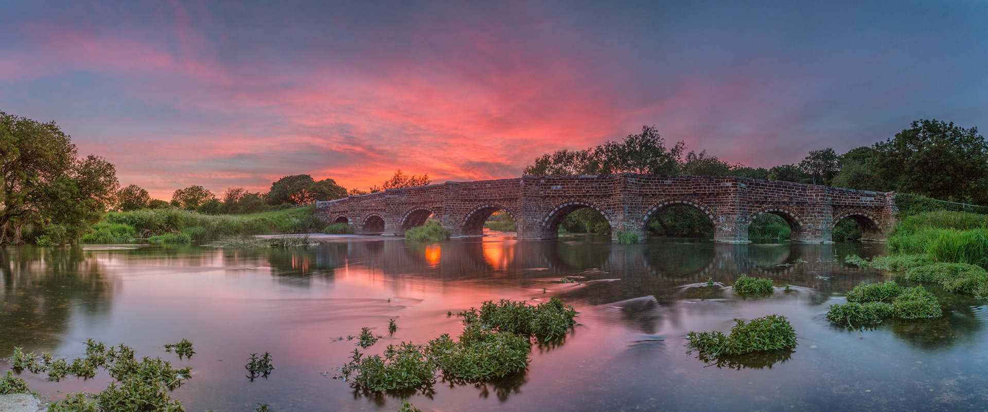 Having failed to get the shot I was after at this location last week, I headed back last night to try again. It didn't look all that promising at first, as a bank of cloud was hogging the horizon, and about 40 mins before sunset the sun all but disappeared - but perseverance won out.. I watched as the clouds over me slowly built with colour just before sunset, the orange/pink glow growing like the clouds were absorbing the colour - a truly remarkable sight to watch!I wanted to capture a bit of movement in the water - so made this image from 9 individual shots taken vertically - each one at 15 seconds, and then stitched together to form a wide panorama capturing all of the bridge (and it's arches!).