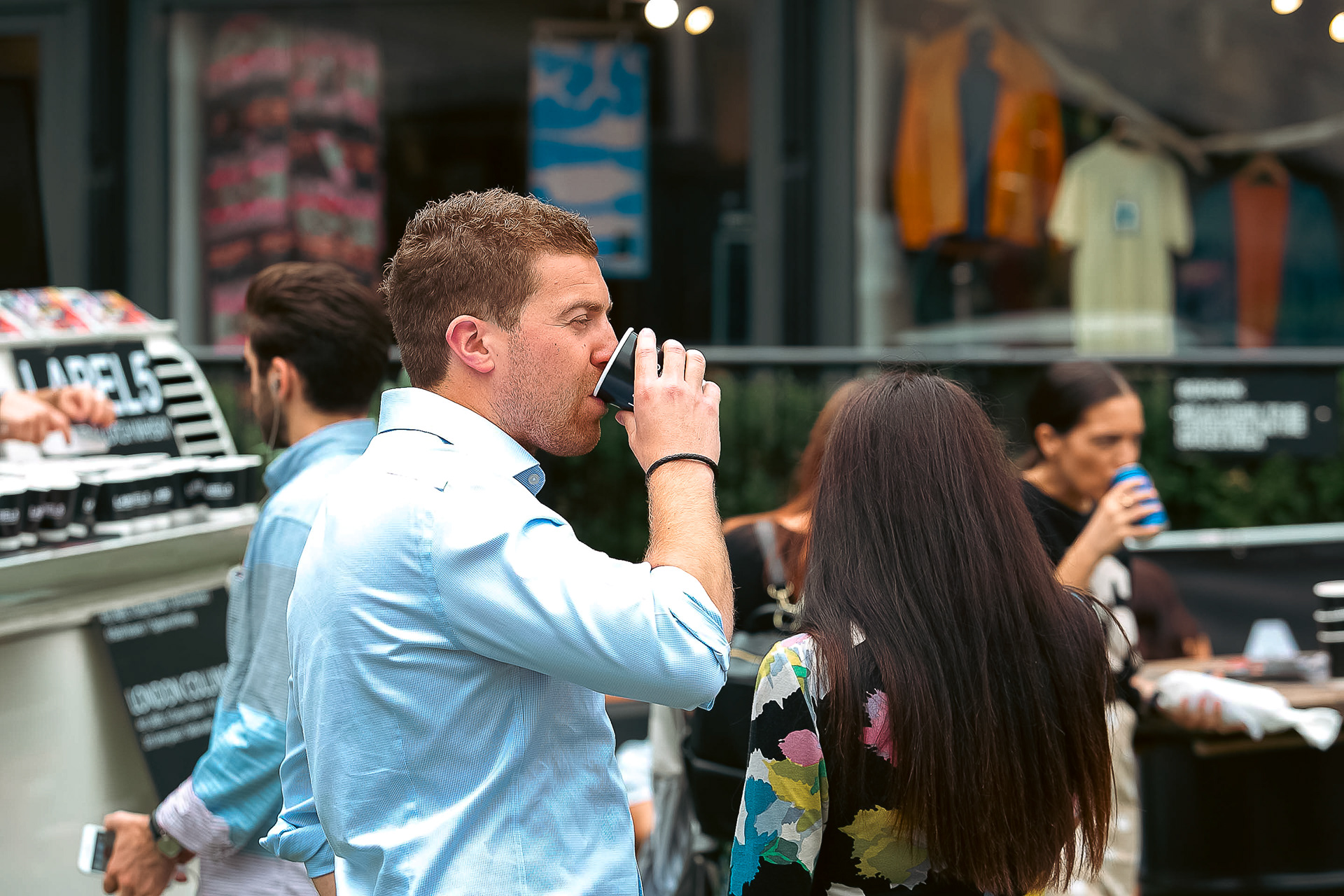 A customer taking a sip of the label 5 drink with next person in line for his own 