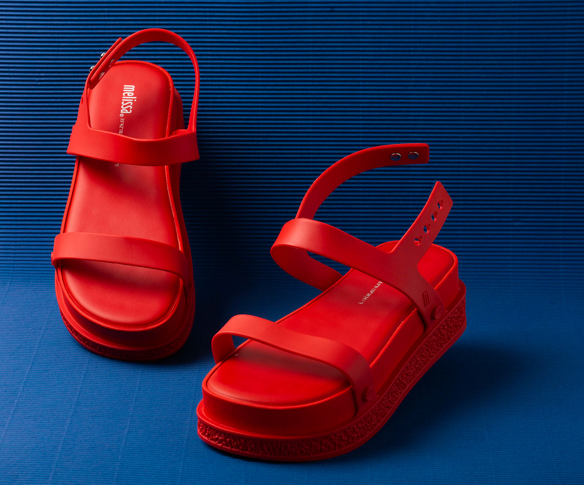 red mellissa shoes on a blue backdrop for a fashion campaign