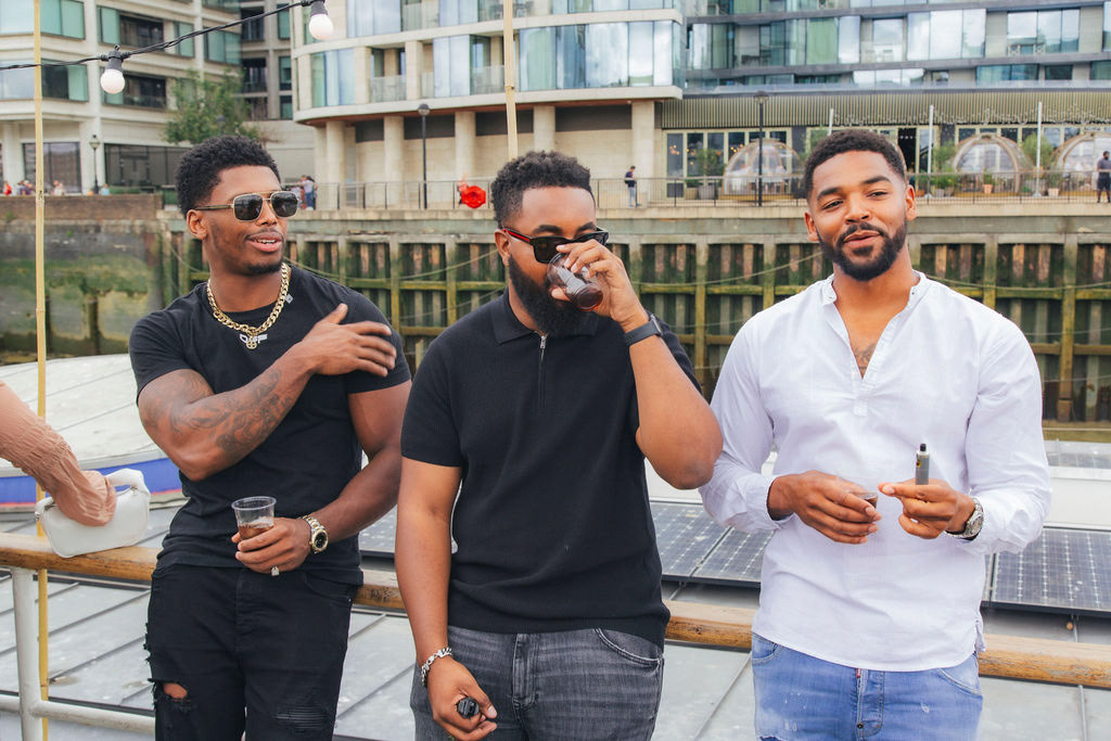 Three male friends enjoying the music and the vibes of the boat party on the thames 