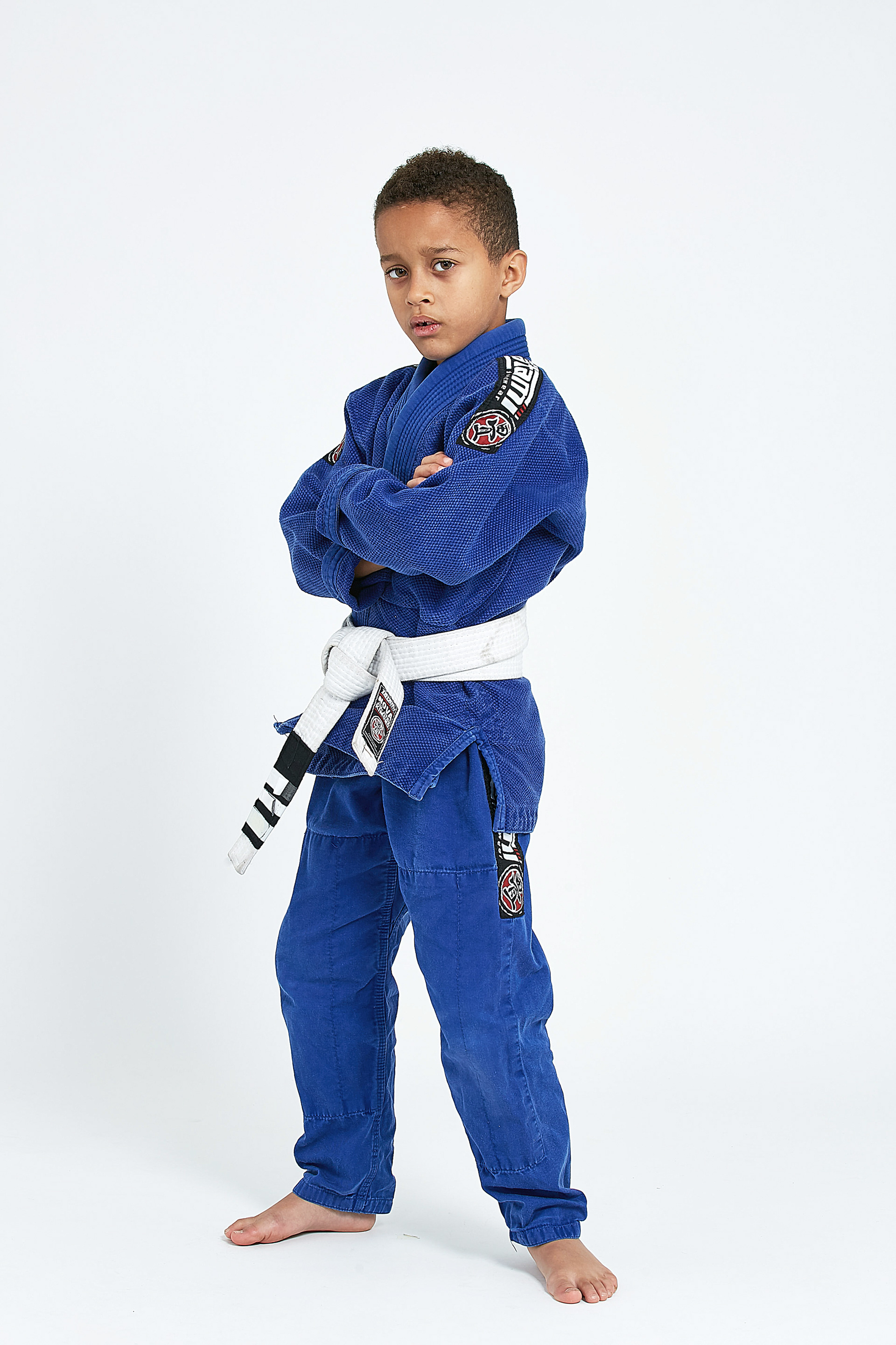 young boy in blue karate uniform in a squaring up with a serious expression on his face. position, taken in a studio with white backgrounds