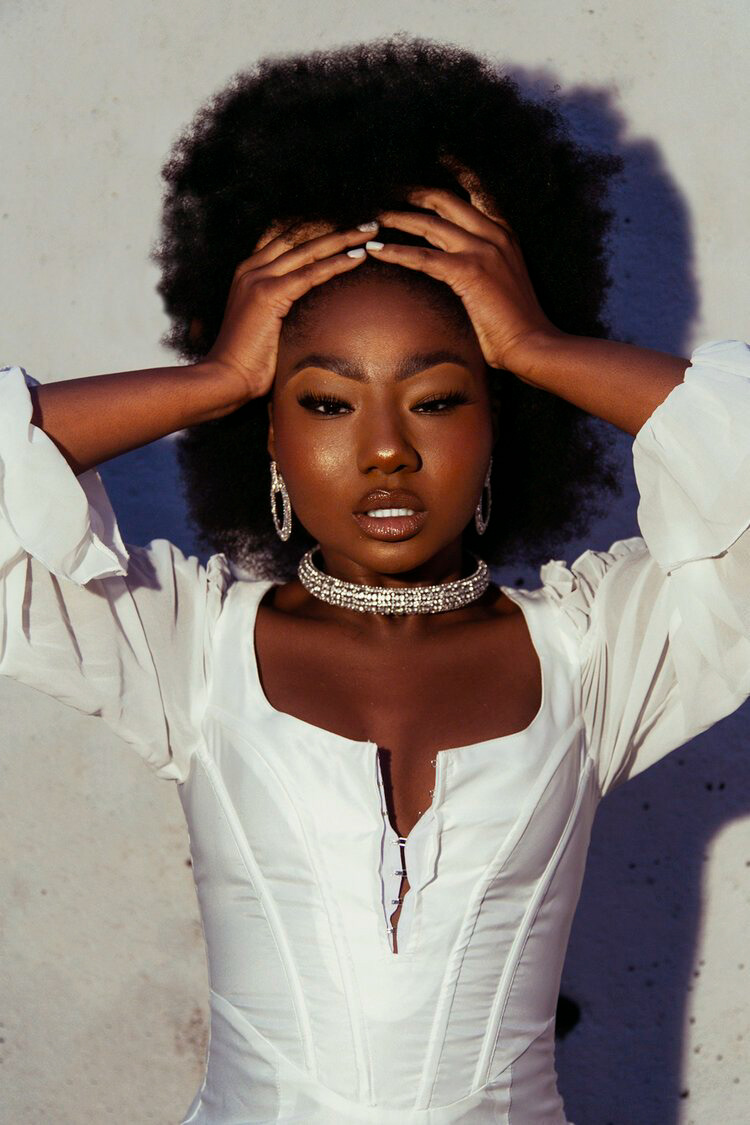 A vibrant model with a white dress and dazzling necklace