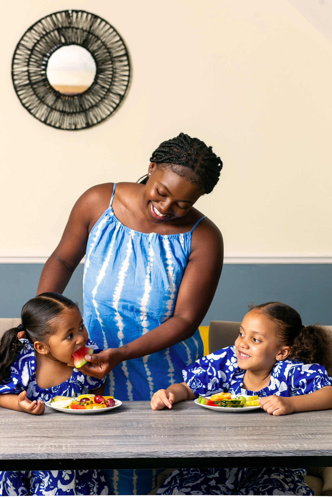 mother feeding her two daughters some fruit after lunch 