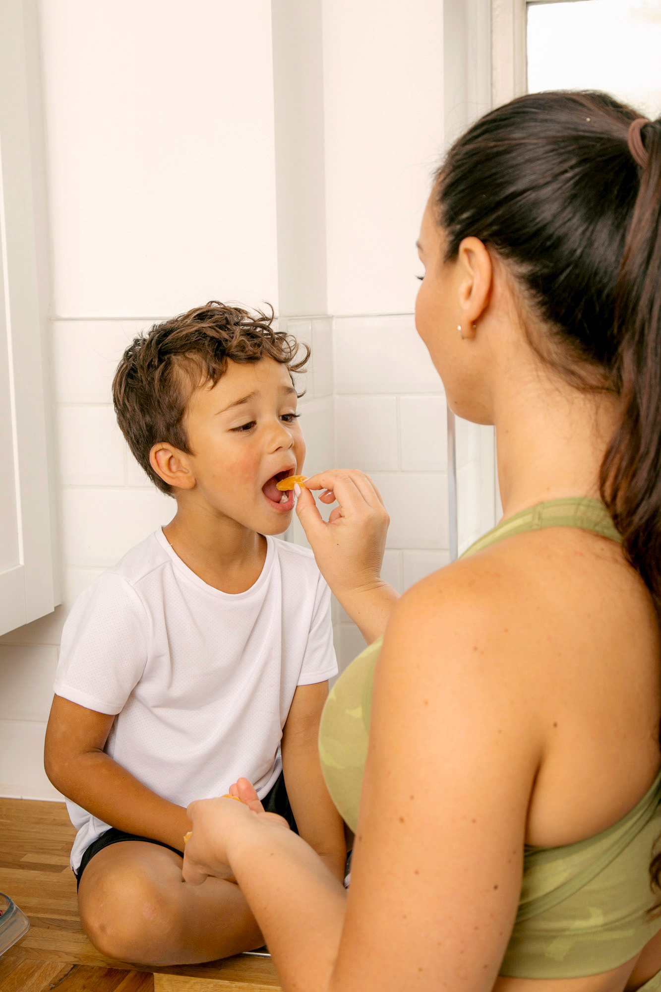 Mother and child enjoying some fruit snacks in the kitchen 