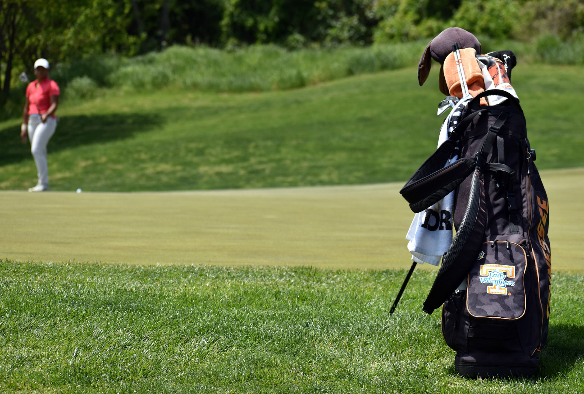 Bailey Davis putts in the background in the direction of her University of Tennessee bag.