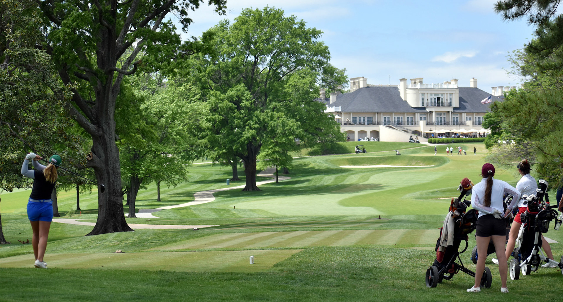 Madeline Foley tees off on 18, featuring a spectacular view of Belle Haven's clubhouse in the background.