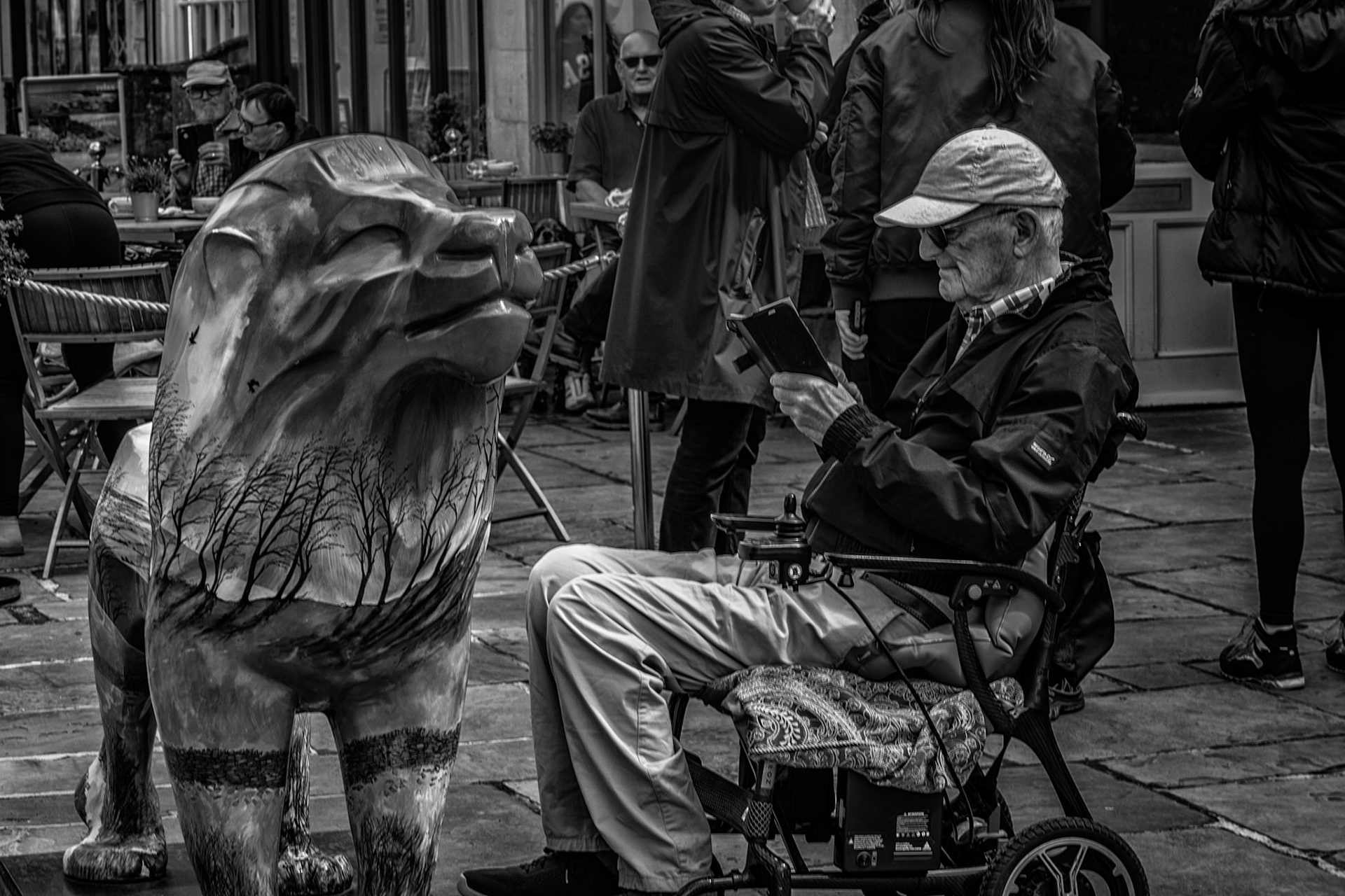 A man, a tablet, and a silent guardian painted with trees. Past and present watch each other on the streets of Corsham.