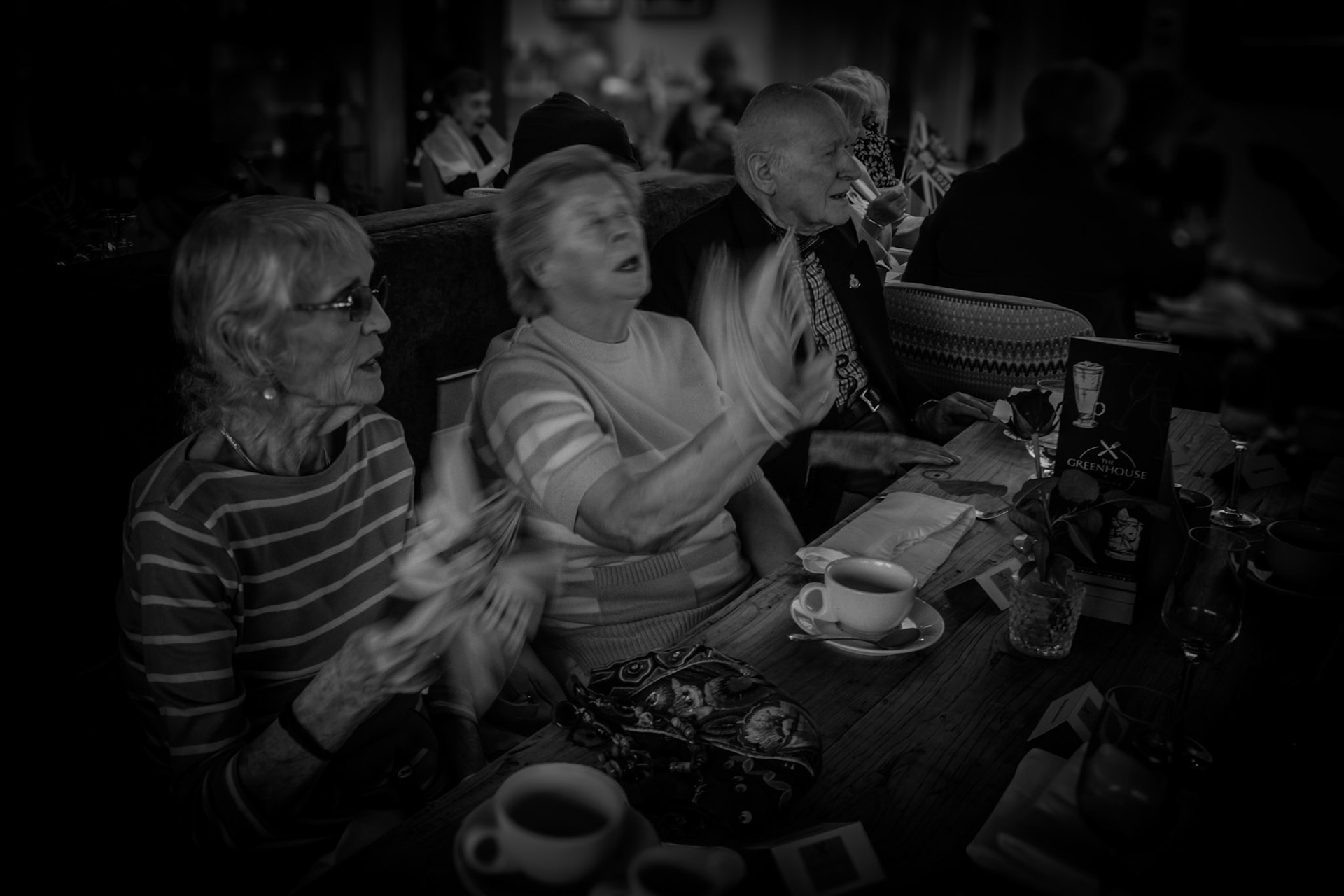 Celebration and camaraderie at a VE Day afternoon tea —an animated moment shared over tea and laughter. The Union flag blurs in motion, echoing the energy and pride of the residents.