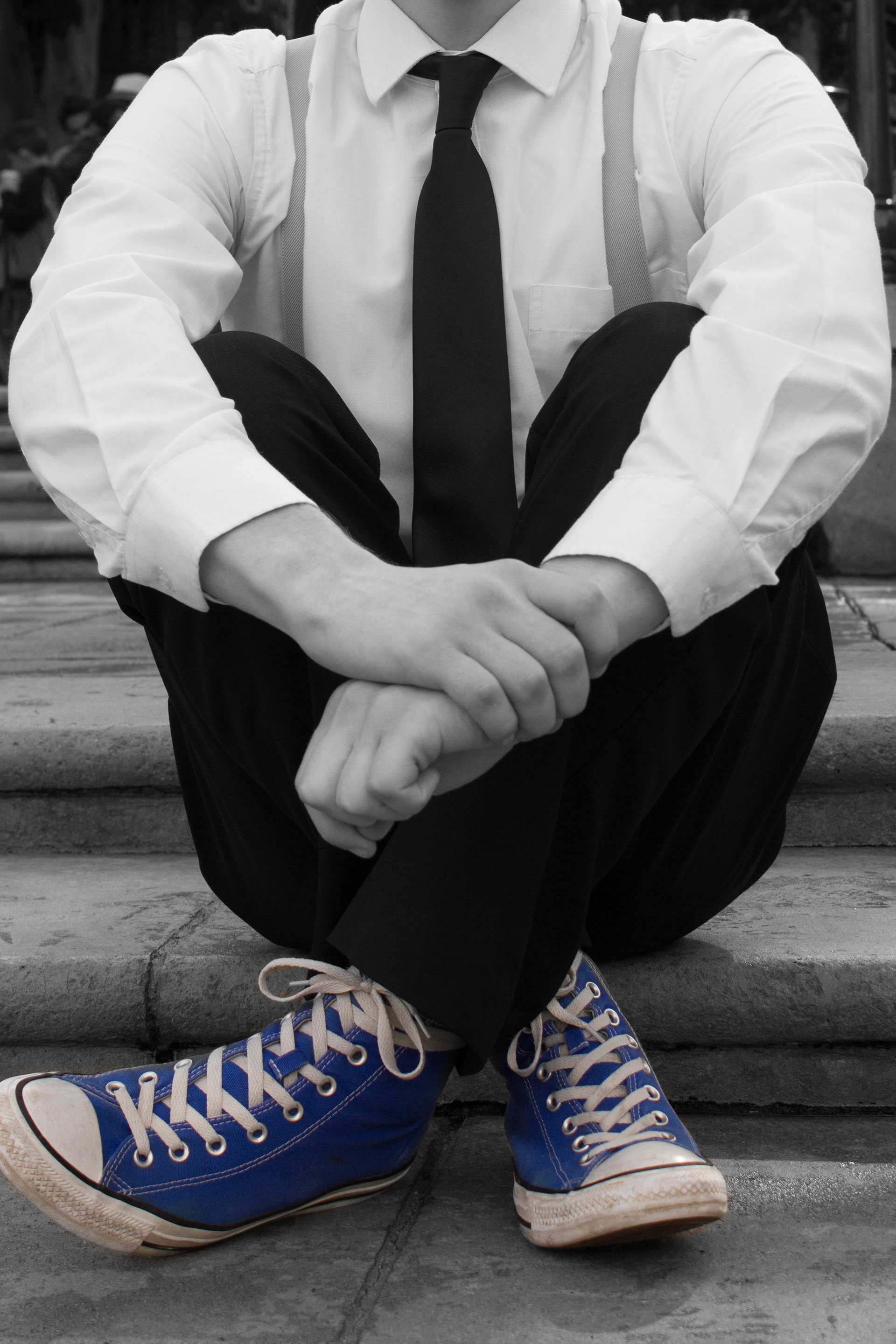 A portrait of a retro dapper man in blue converse shoes wearing suspenders
