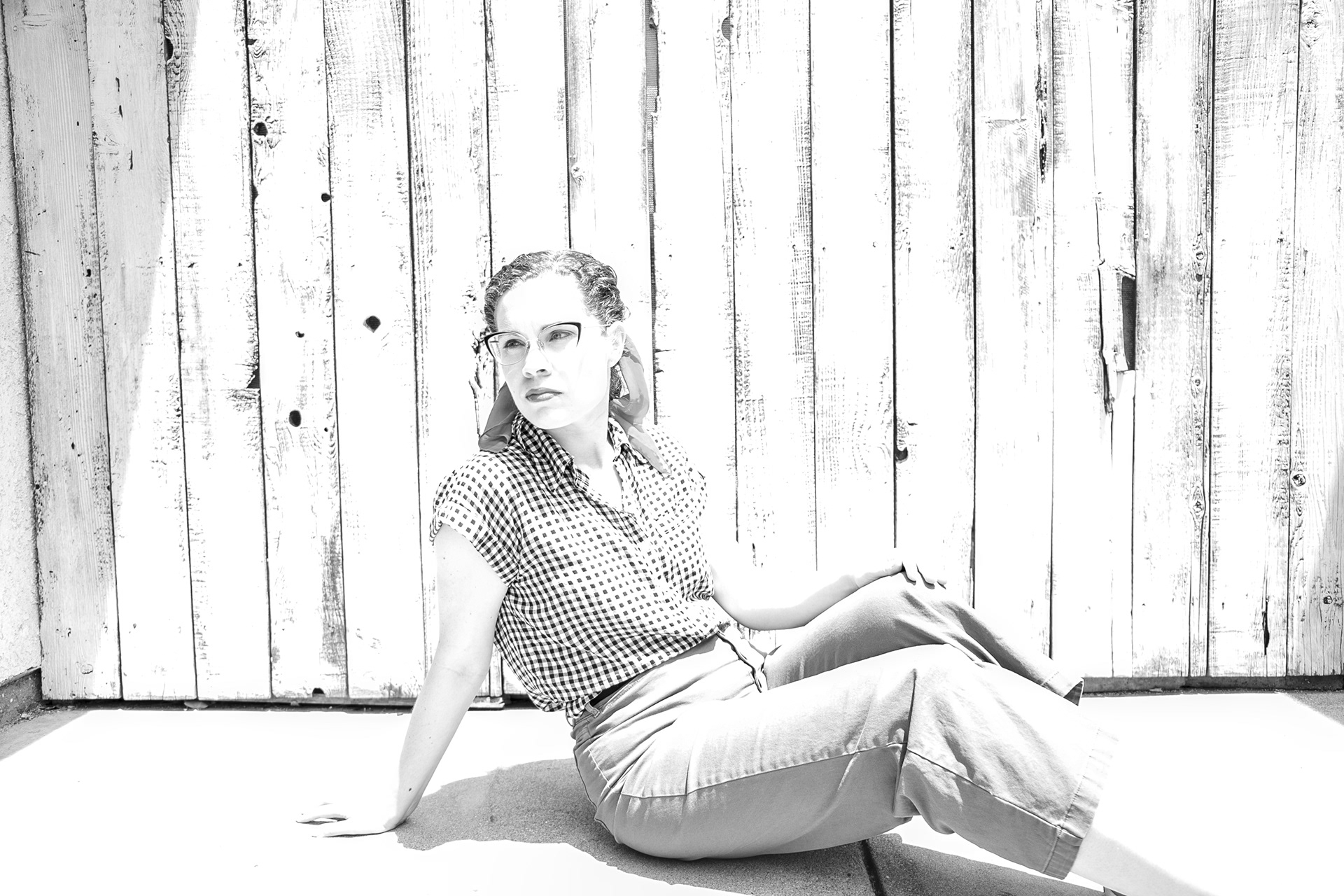 Rockabilly vintage outfit. A retro dressed woman poses in a portrait Infront of a wood fence.