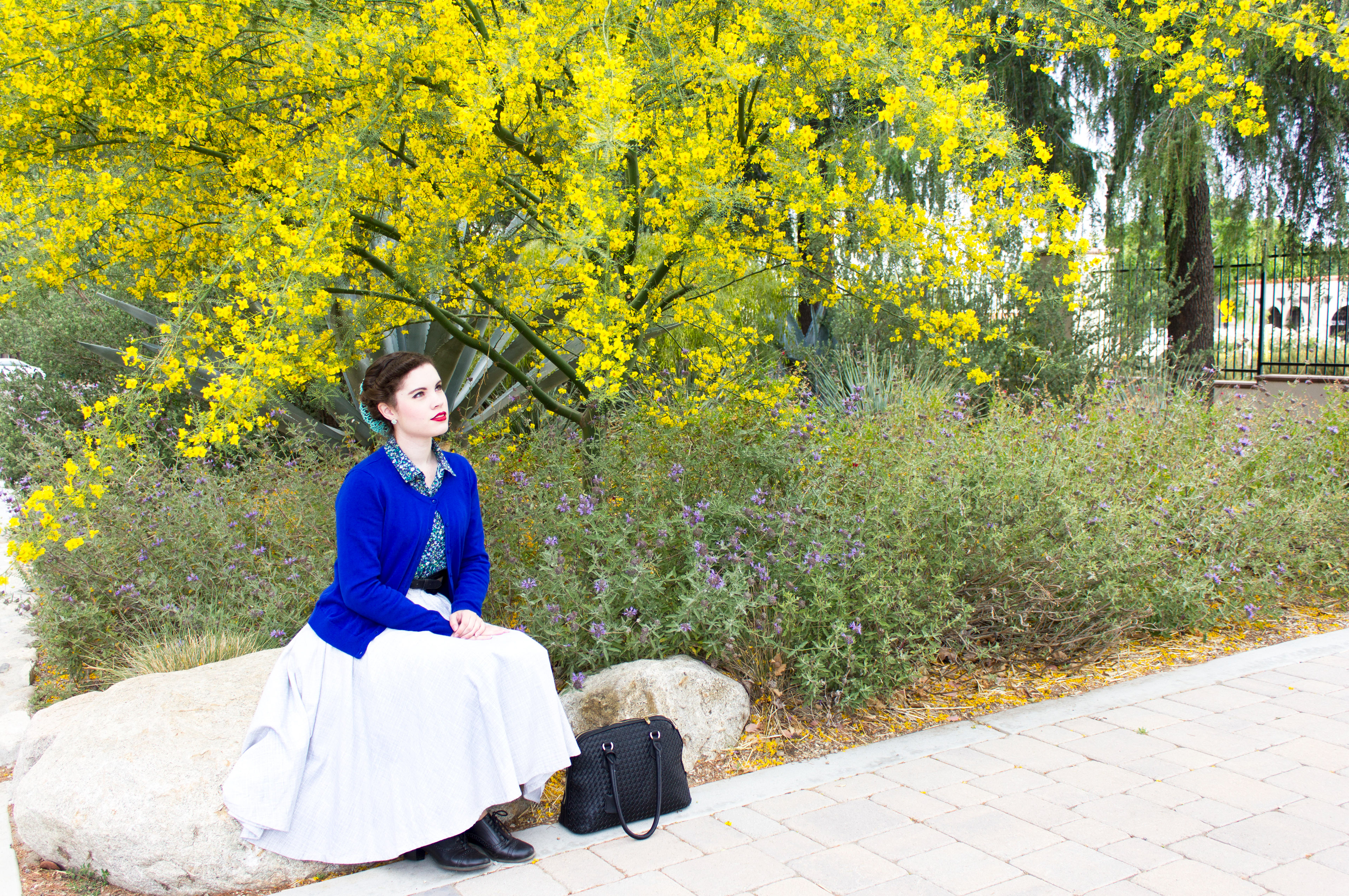 The vintage blue sweater pops against the yellow of the flowering tree in this vintage fashion portrait.