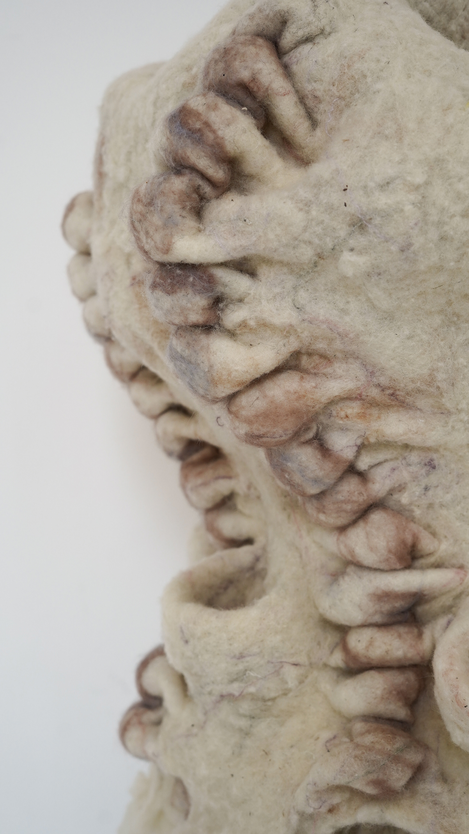 Close-up detail of the woolen texture from the sculpture with us by Ludmila Bubanova. Hand-felted organic wool in shades of pink, purple, and blue, mimicking collective human skin with veins and thick dark stitching.