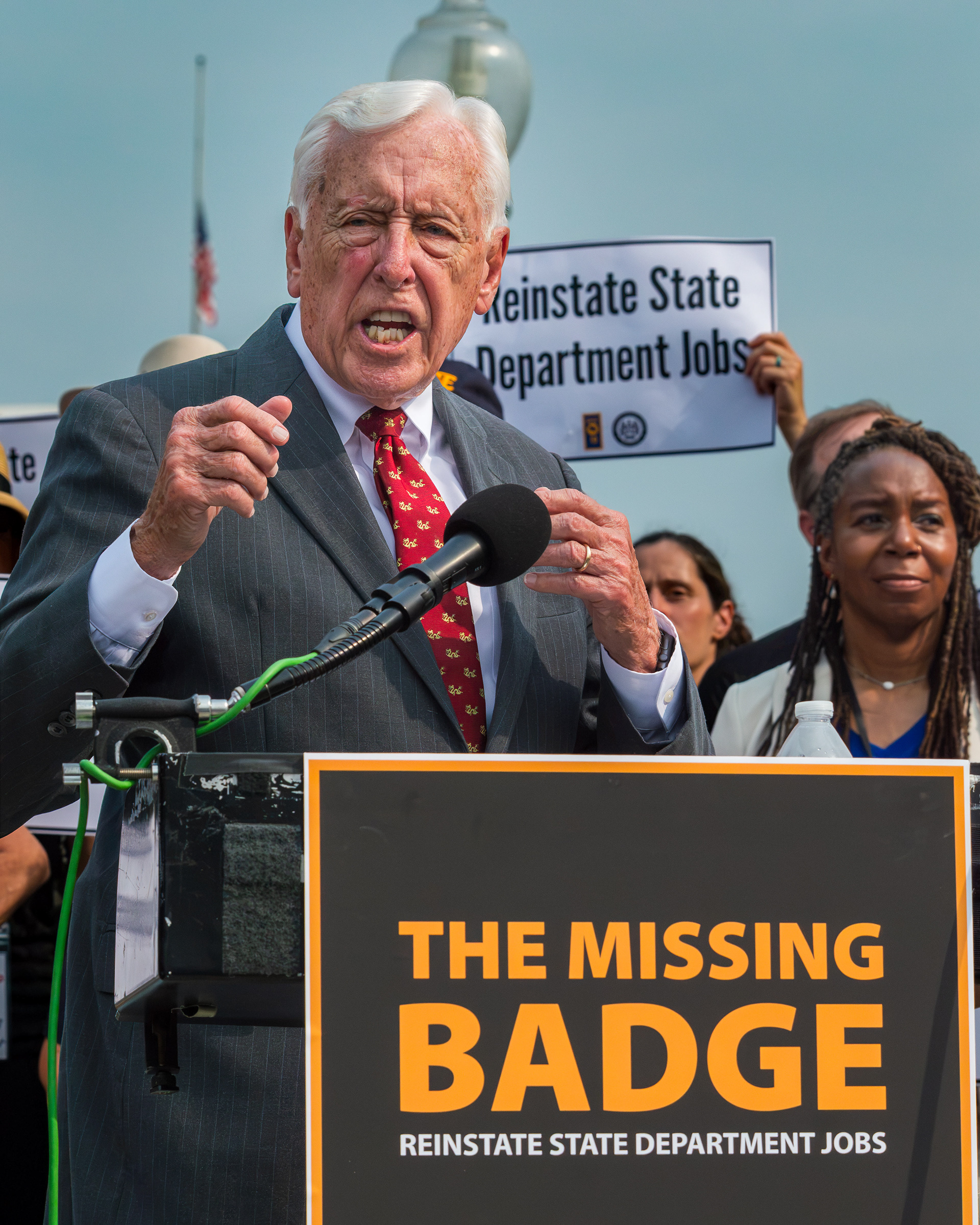 An older white man in a suit giving a speech at a podium.