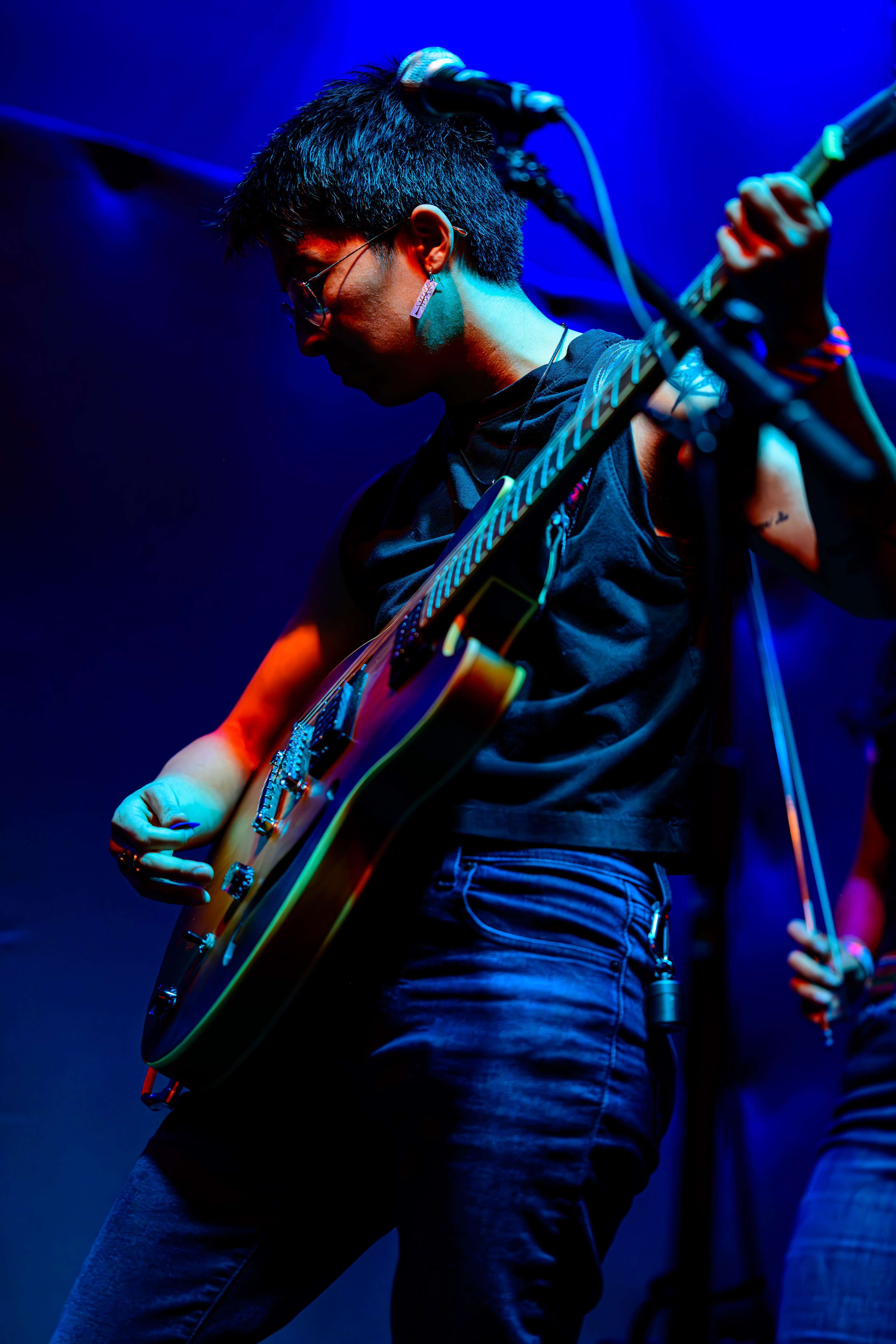 A woman with short black hair playing the guitar on stage.
