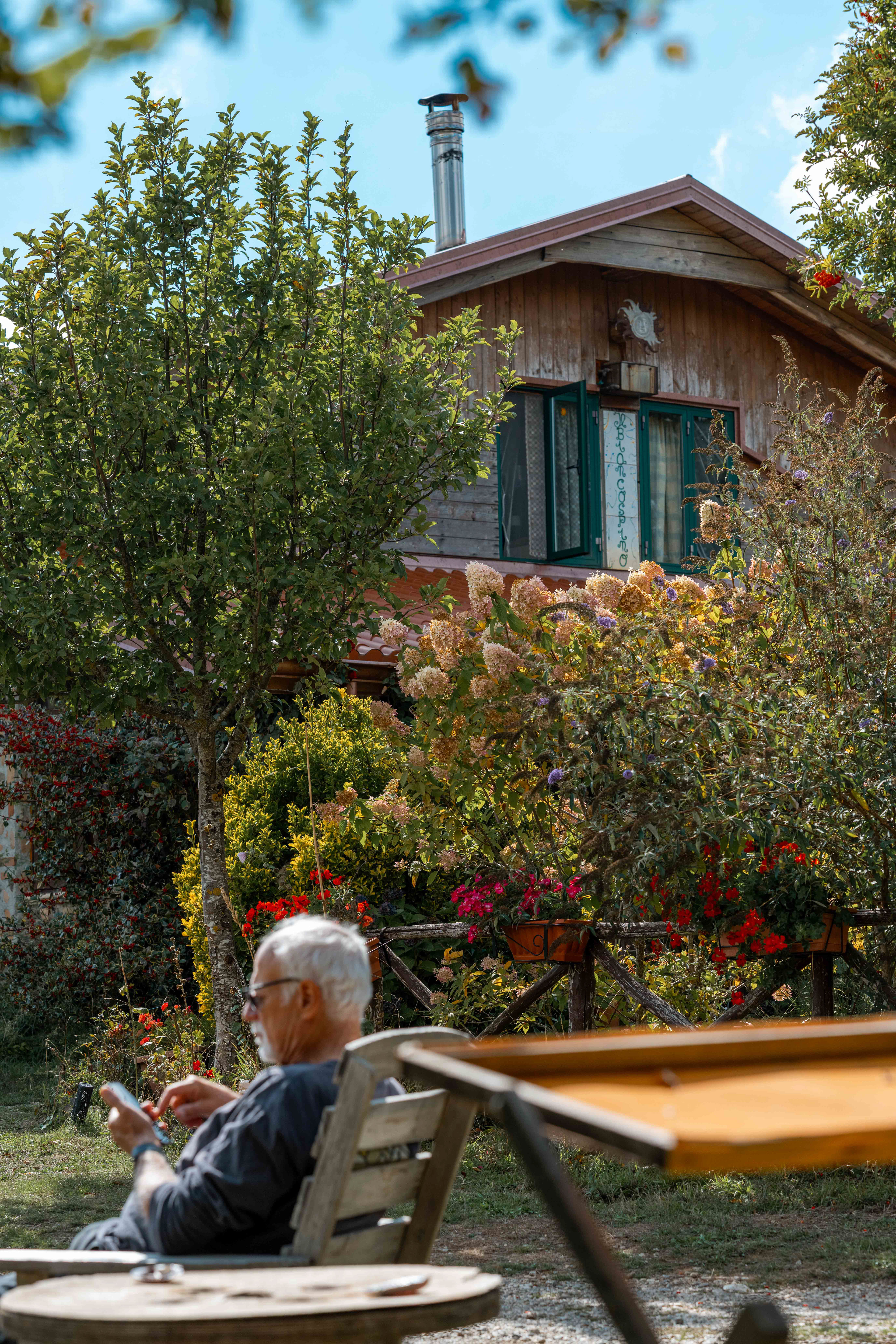 A man relaxing in front of a mountain cabin.