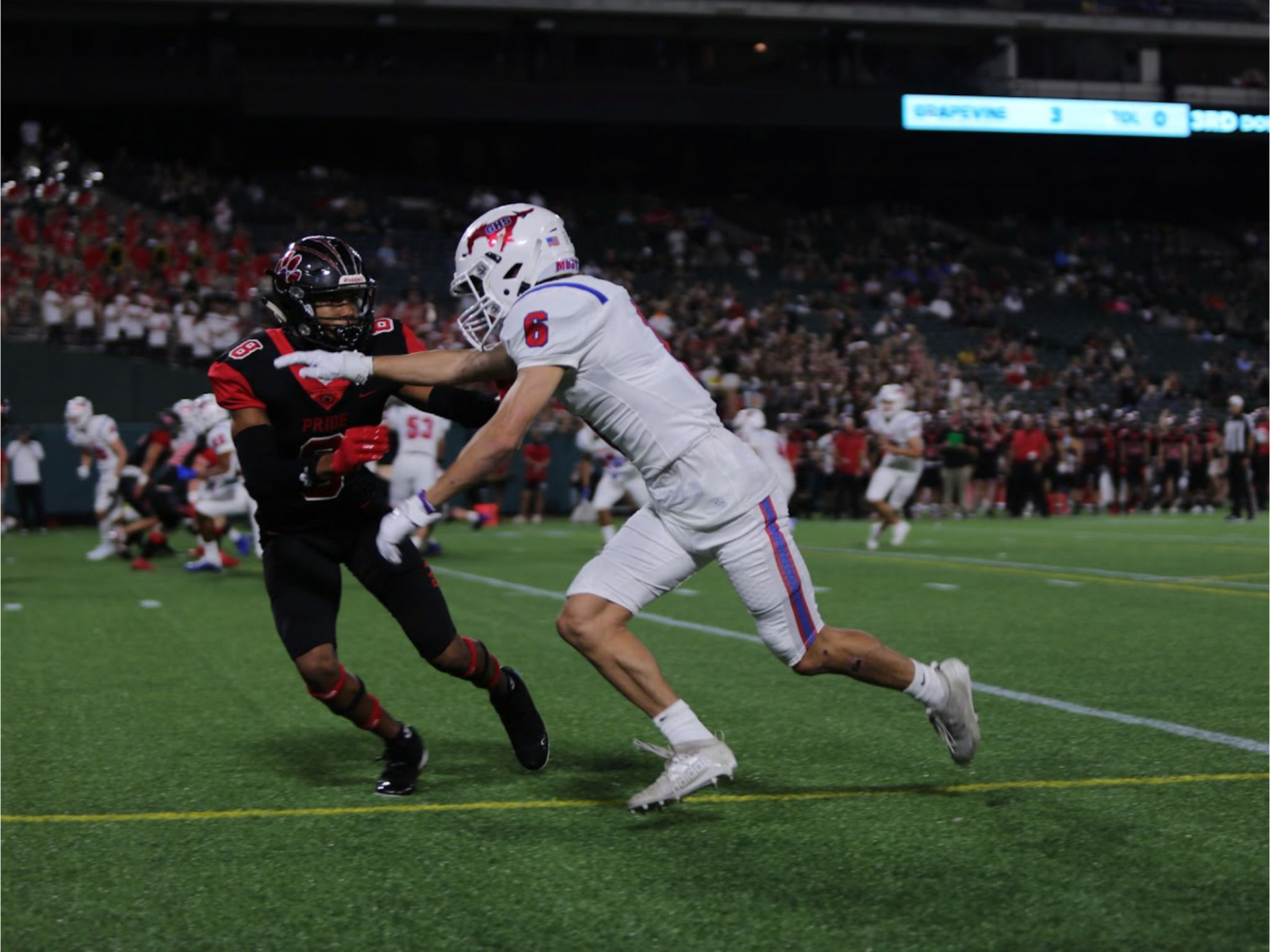THE RUSH- Grapevine Mustang player No. 6 defends himself against Colleyville Heritage’s No. 8 during an offensive play in the annual rivalry matchup known as The Battle of the Red Rail, held at Mustang-Panther Stadium. The game ended in a 42-7 loss for the Mustangs. By Alaina Jones