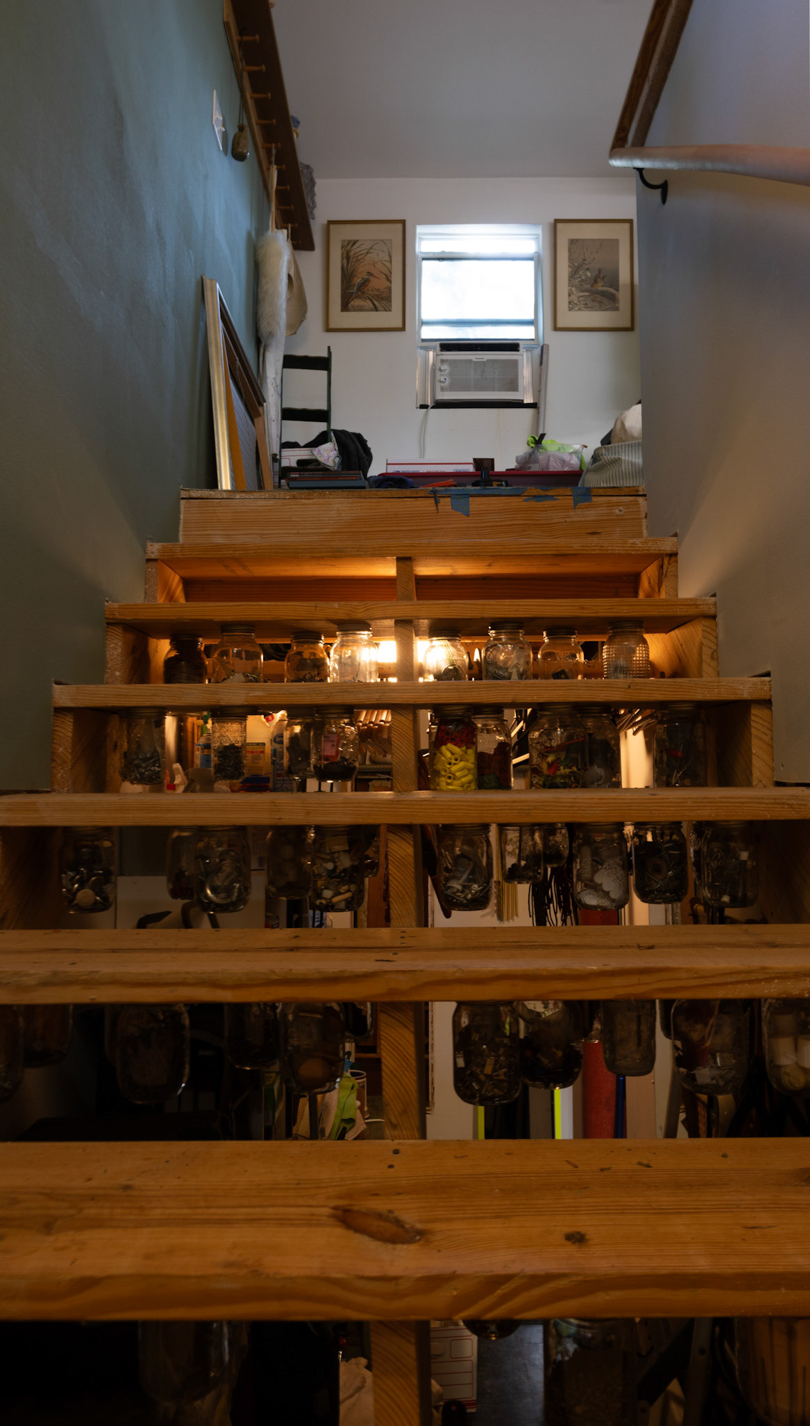 STORAGE WITH A TWIST- Leslie Kregel creatively stores her art supplies in glass jars, securely screwed onto the underside of the stairs on April 29, 2024, keeping her workspace organized and accessible. This inventive solution maximizes space but adds a unique, functional touch to her studio Kregel explained. By Alaina Jones
