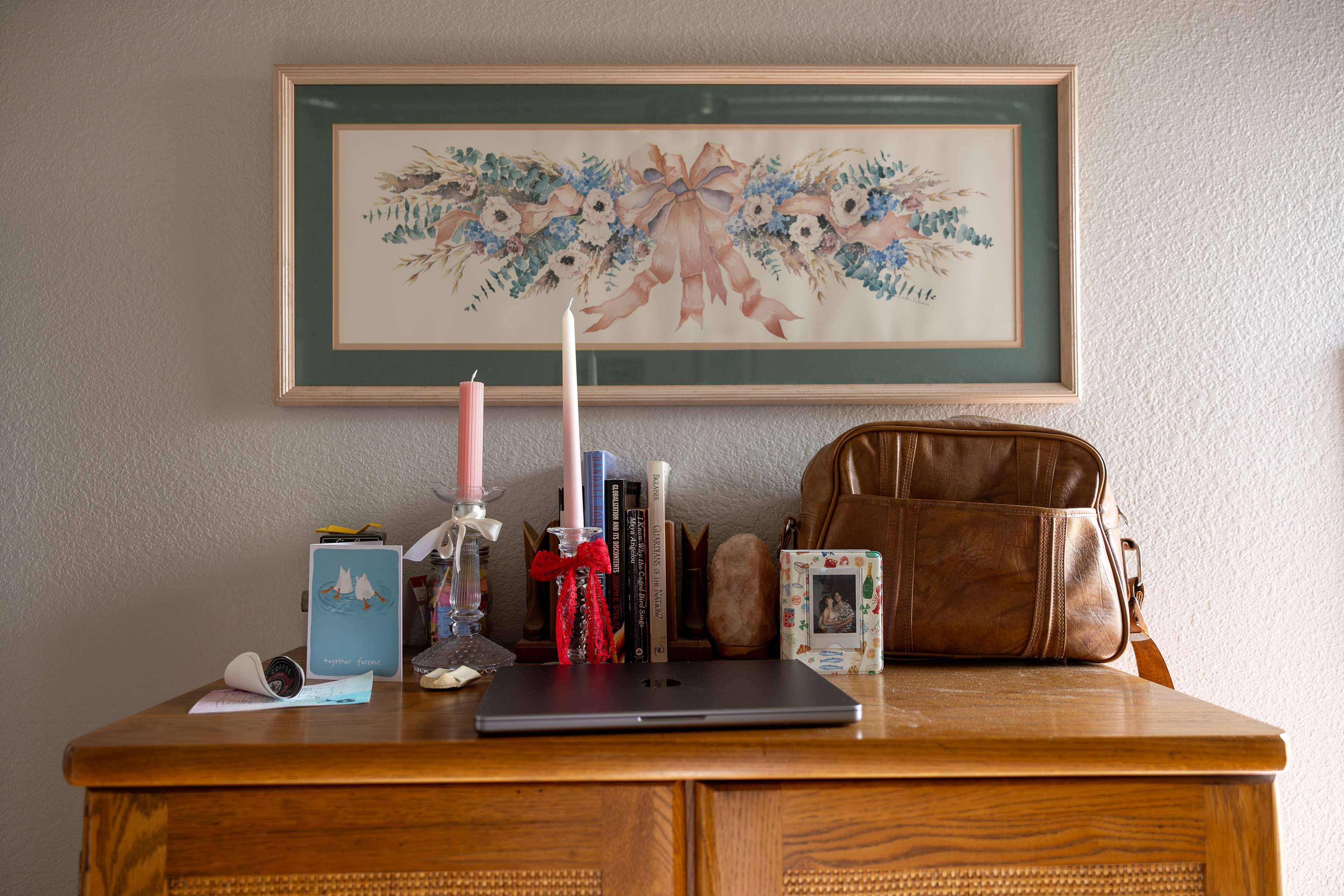 MEANINGFUL- Atop White’s dresser sits a collection of items meaningful to her on April 24 , 2025, a photo book covered in pictures of her and her fiancé, Bryce Workings; a camera bag; her essential laptop; and books she cherishes, including Globalization and Its Discontents by Joseph E. Stiglitz and I Know Why the Caged Bird Sings. A journal also rests nearby, which she uses to process her emotions as she navigates the final stages of school and moving to a new state. Photo by Alaina Jones
