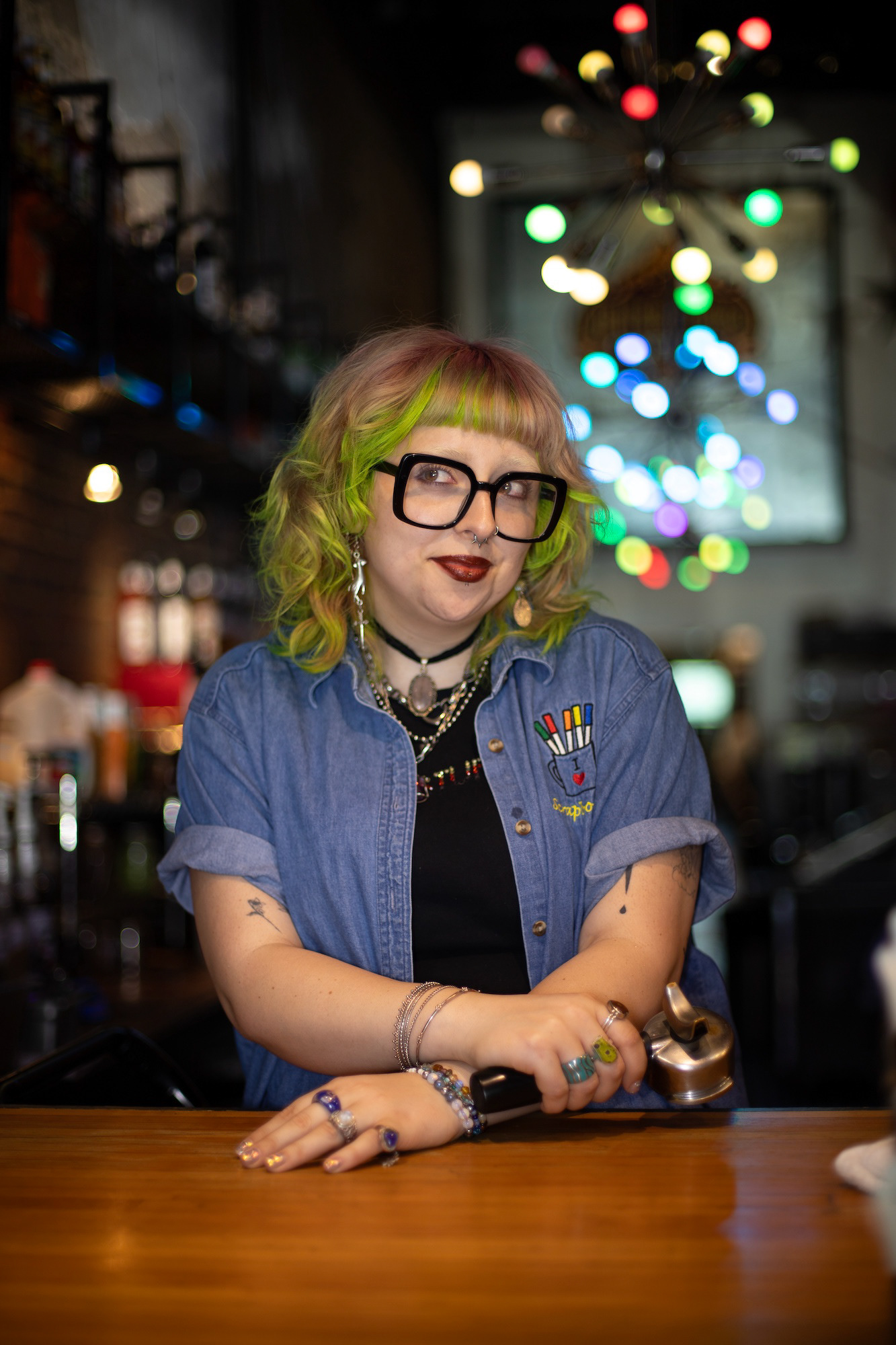 Under the lights at Jupiter House in Denton Barista, Brisa Kennedy, poses for a photo on April 15, 2025 during her shift. She has worked for Jupiter House for two years. “I love working at Jupiter House because it feels like a club,” Kennedy said. Photo by Alaina Jones