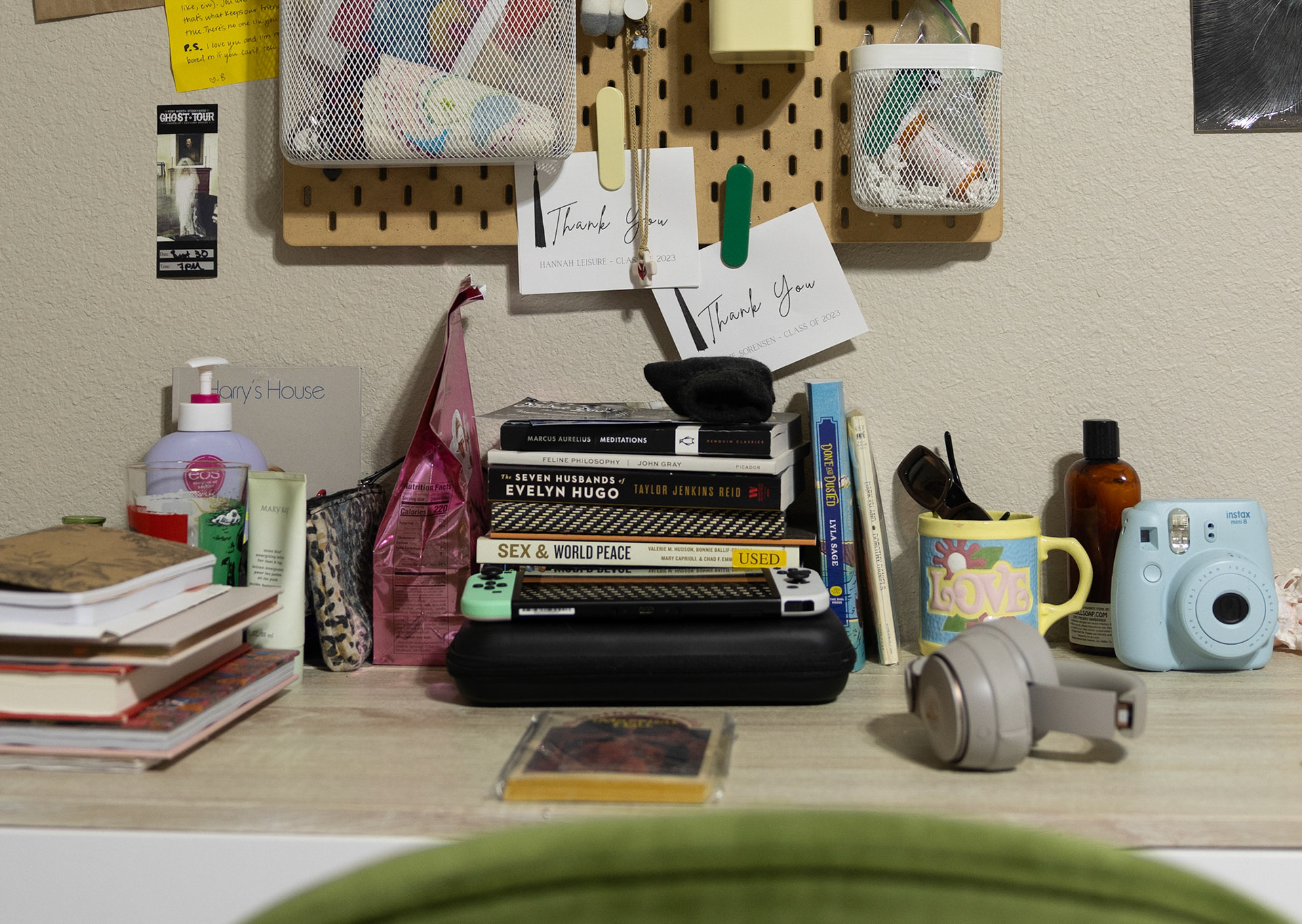 CROSSED WIRES- Her desk is covered in her essential items, text from her studies, favorite books, Nintendo Switch, headphones, sunglasses and more on April 1, 2024. “My desk is like a safe space for me. It is where I read, journal, study and relax,” Reed said. Reading helps quiet her mind, journaling helps her process emotions, and playing video games helps her find a peaceful escape from her day to day life. Photo by Alaina Jones