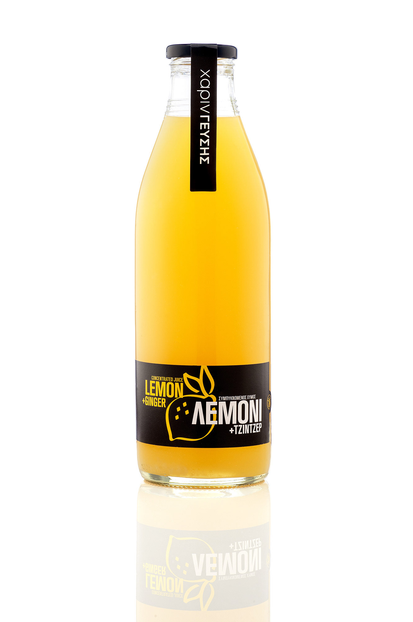        Studio product shot: Γυάλινο μπουκάλι με συμπυκνωμένο χυμό «Λεμόνι + Τζίντζερ» της εταιρείας «χάριν ΓΕΥΣΗΣ», τοποθετημένο σε λευκό ανακλαστικό υπόβαθρο με μαύρη ετικέτα και μαύρη ταινία ασφαλείας στο πώμα.  ,   Commercial product photography of a glass bottle containing "Lemon + Ginger" concentrated juice, featuring a striking black label and safety seal, isolated on a seamless white background with a soft bottom reflection.