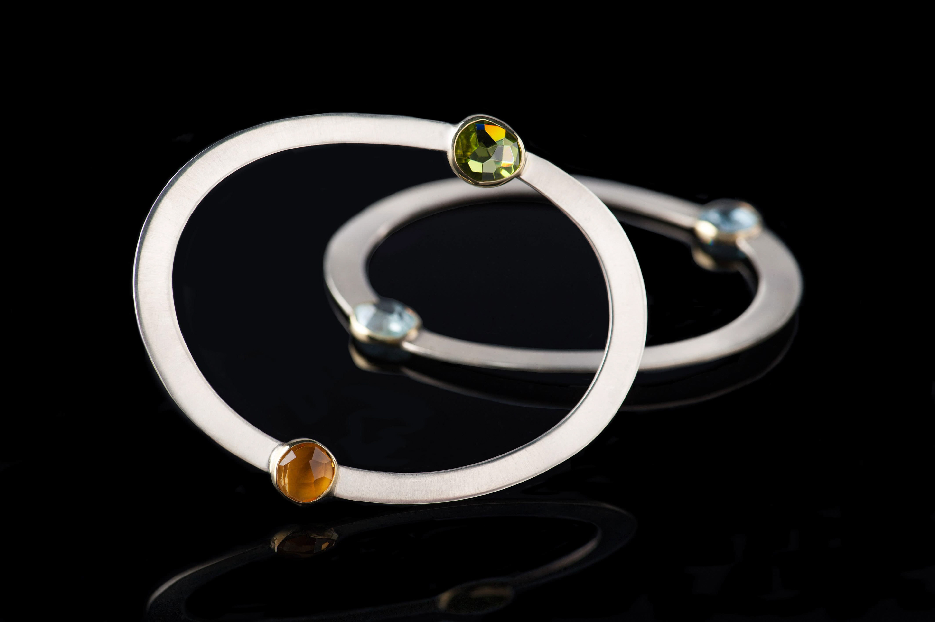 Margoni jewellery: ασημένια βραχιόλια με δύο ημιπολύτιμες πέτρες ακουαμαρίνα σε μαύρο φόντο με αντανάκλαση