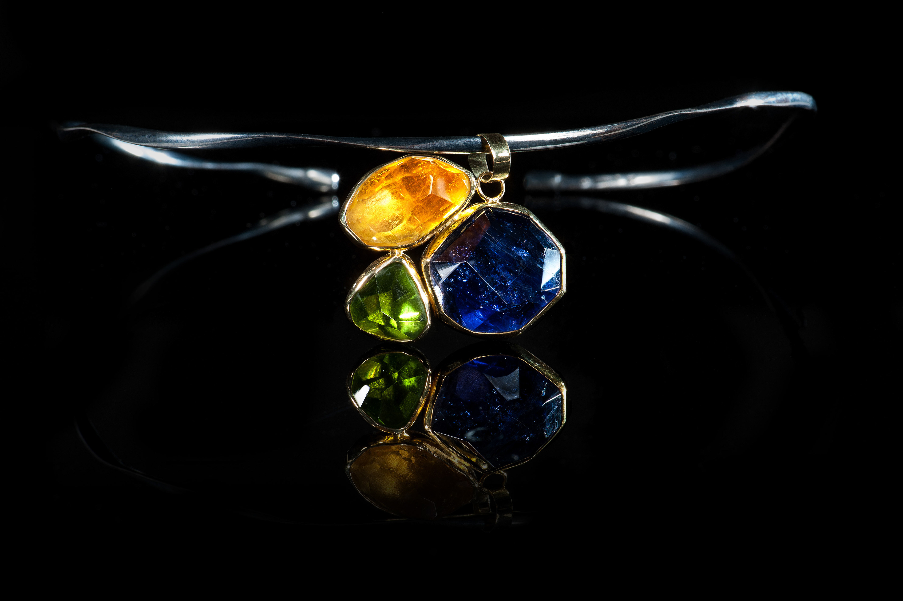 "Margoni jewellery: μενταγιόν χρυσό σε ακανόνιστο σχέδιο με τρείς διαφορετικούς ημιπολύτιμους λίθους σε ασημένιο κολιέ σε μαύρο φόντο "