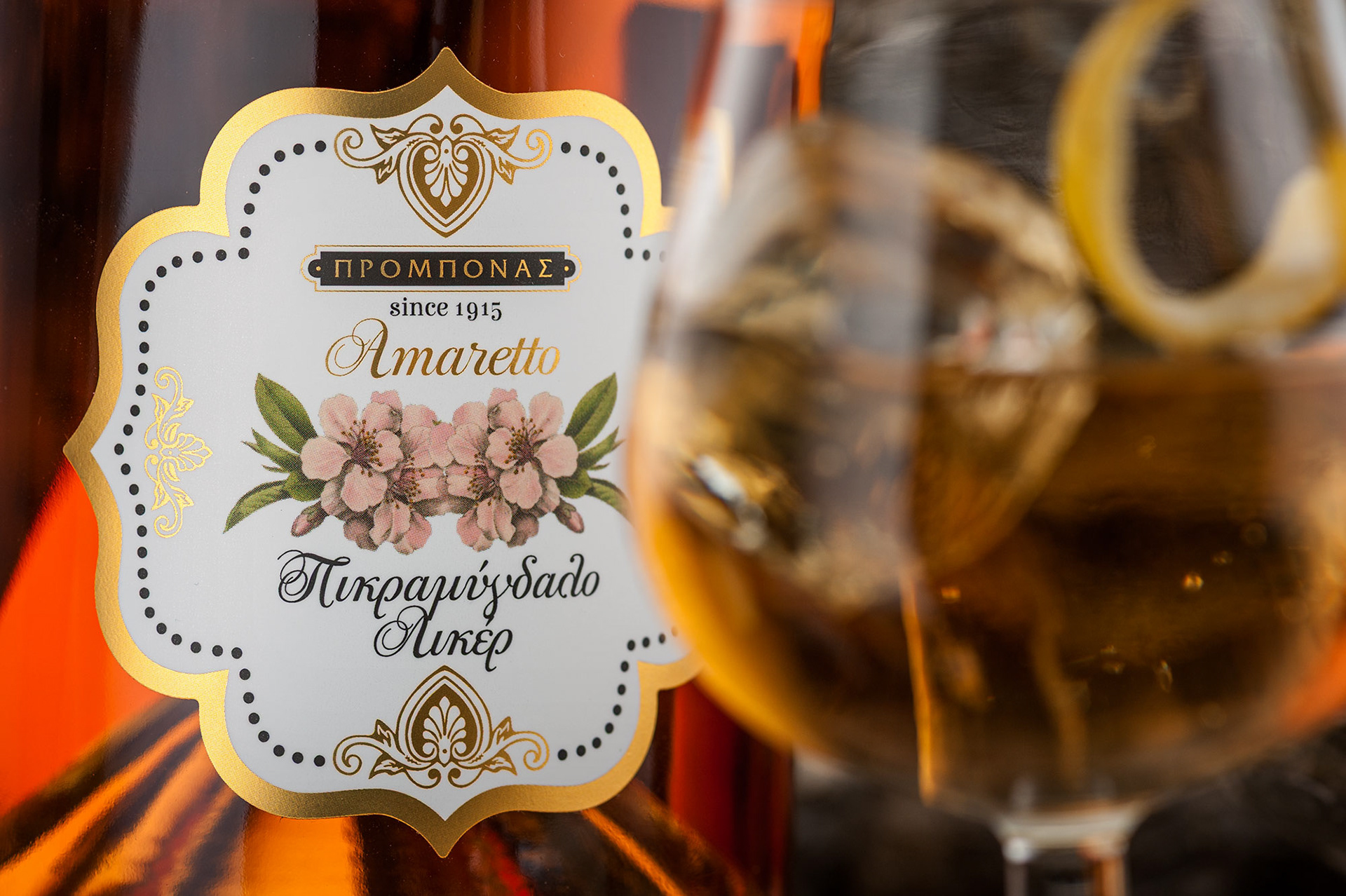 κοντινό πλάνο ετικέτας μπουκαλιού amaretto με ποτήρι γεμάτο θολό 